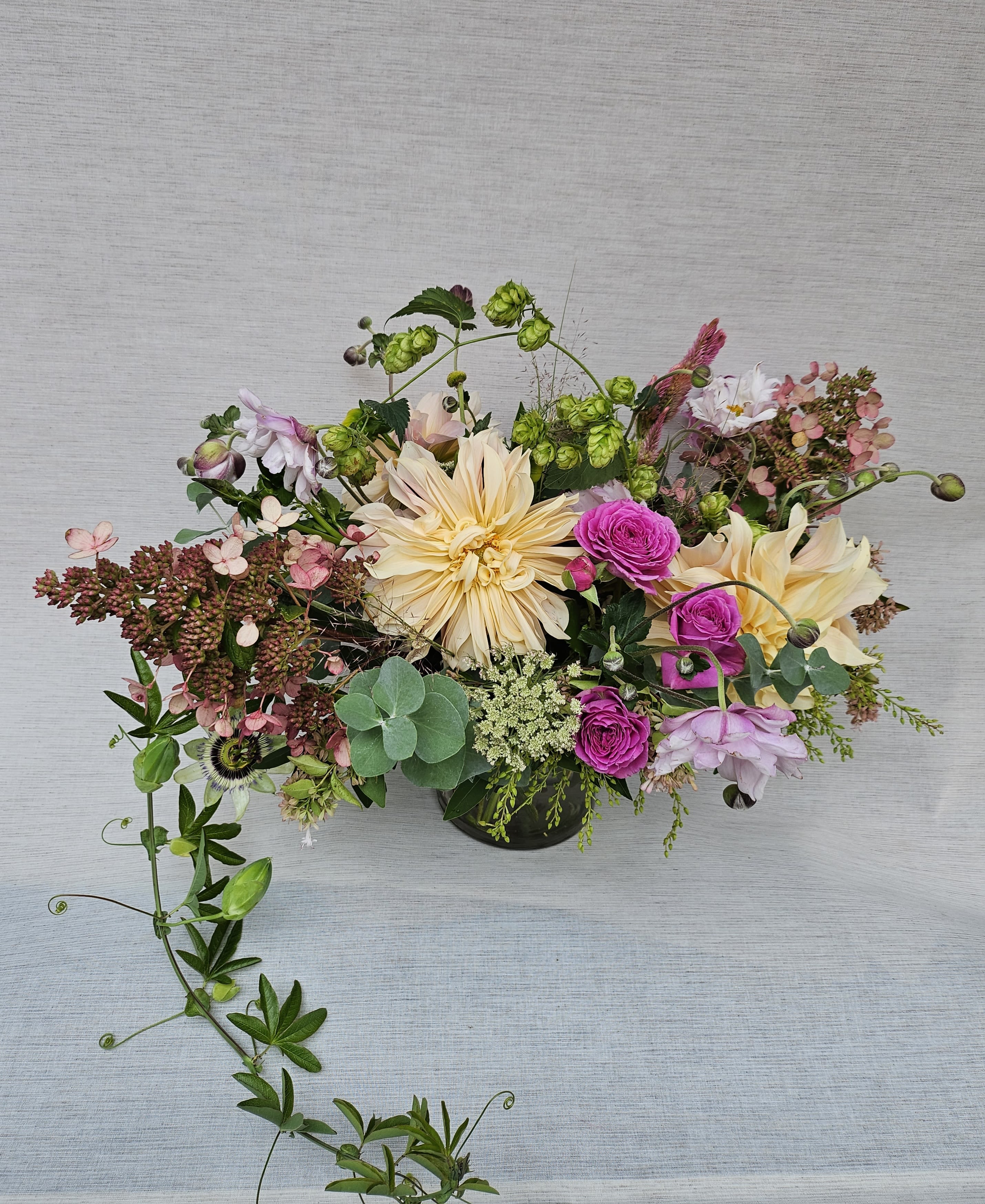 Low centerpiece of peach dahlias, fuchsia spray roses, and mixed blooms in a round glass vase