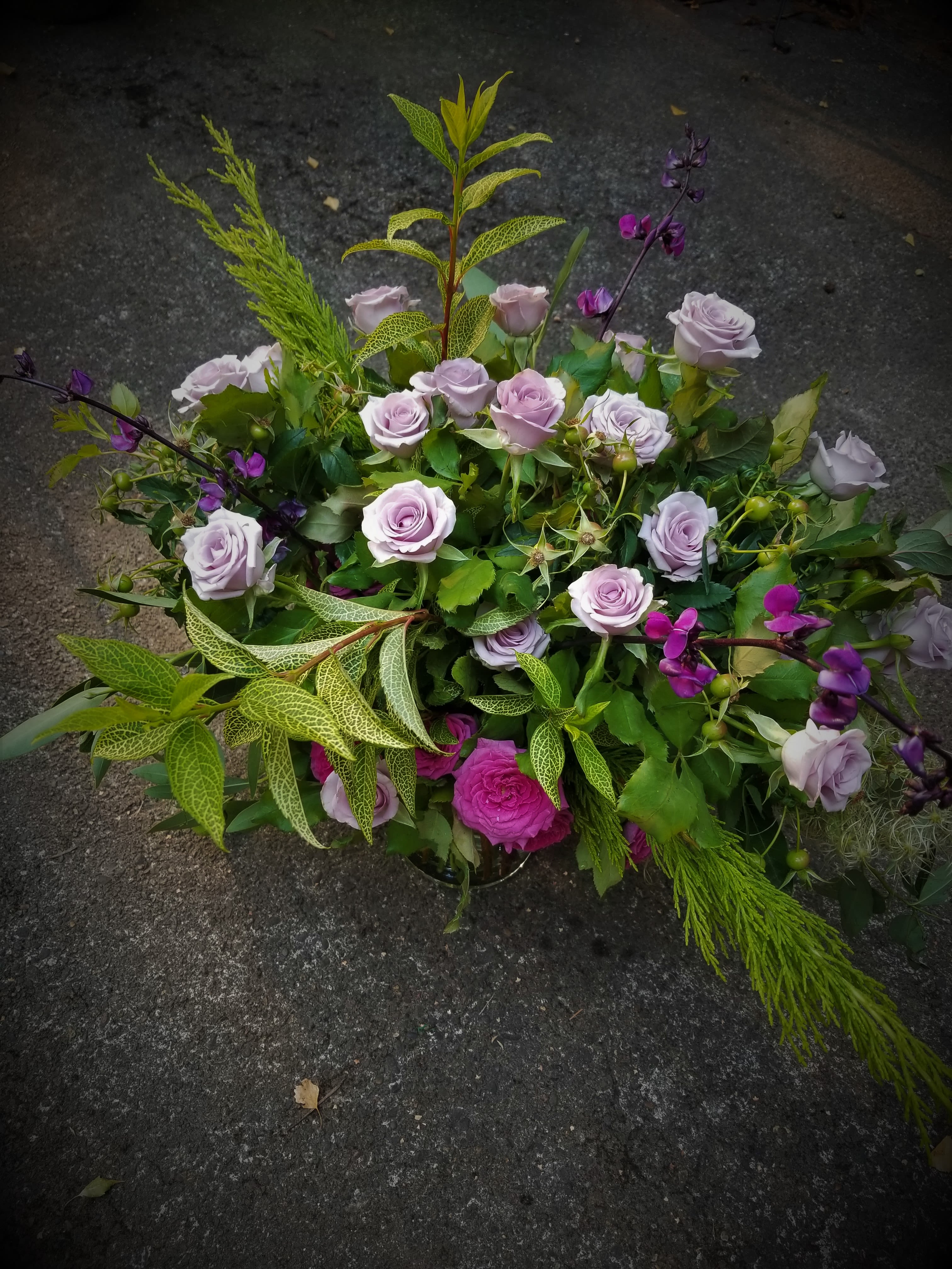 Low garden-style arrangement of lavender roses with bright pink accents and airy greenery