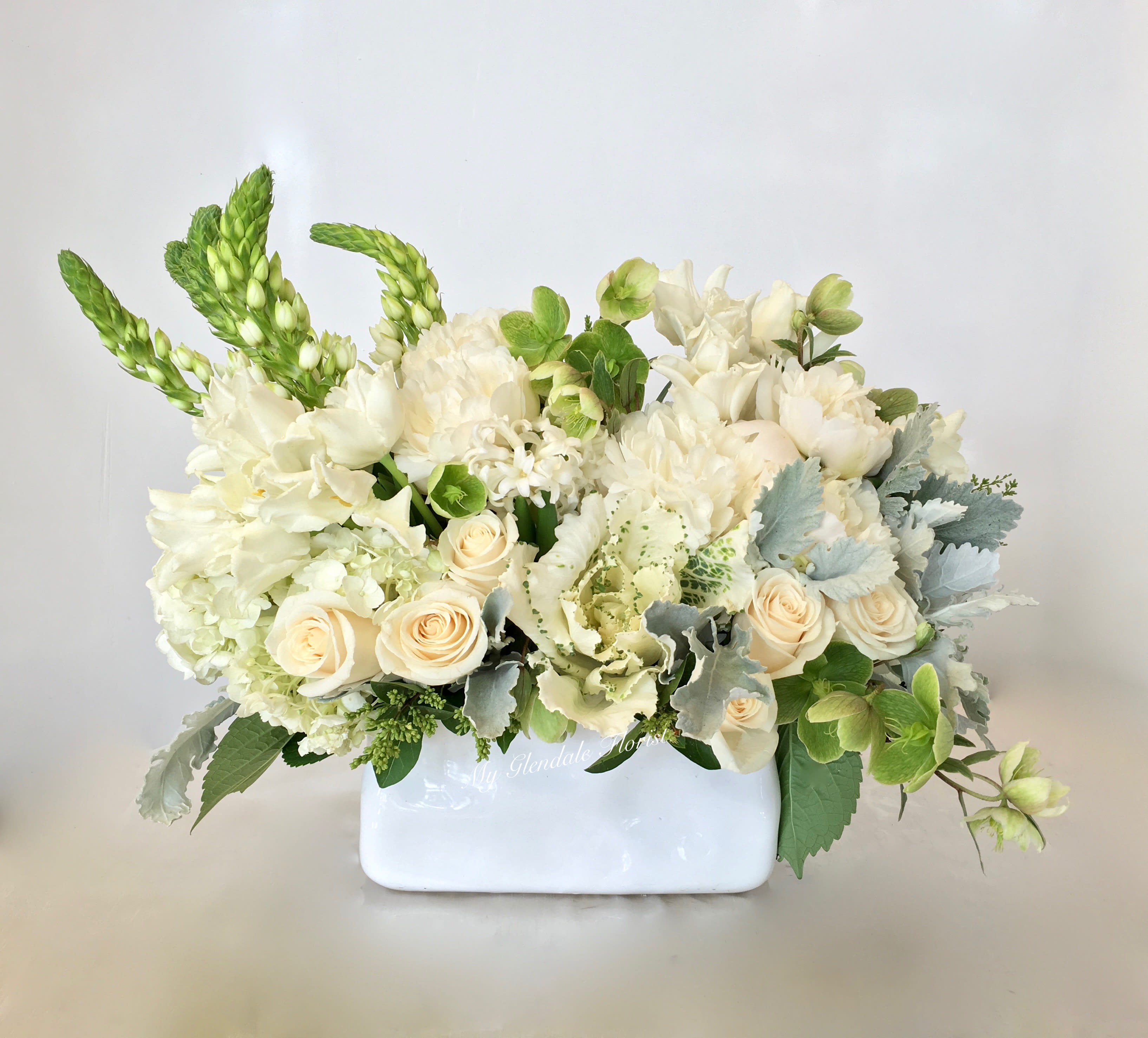 Low white and cream flower arrangement with roses in a rectangular white vase