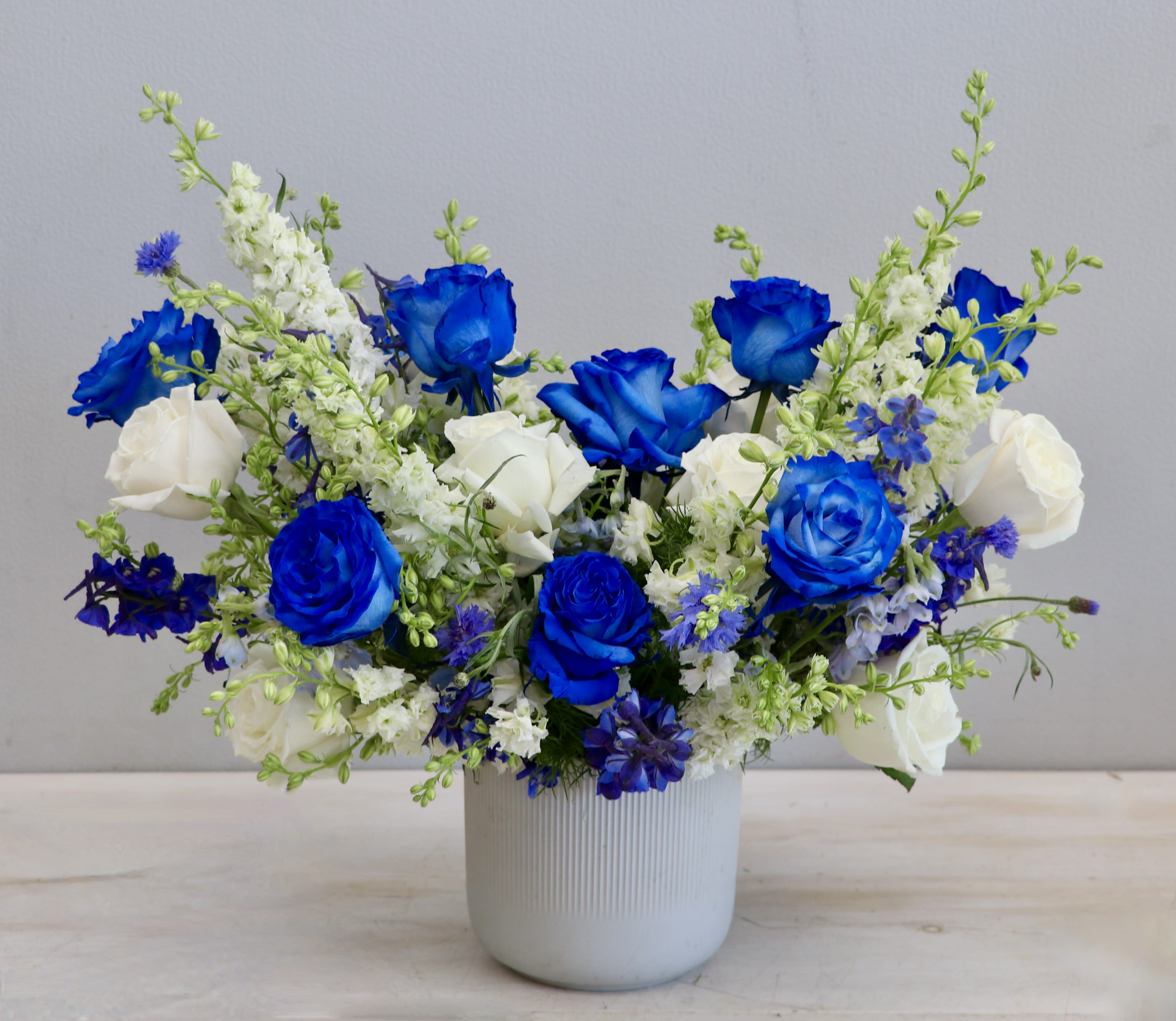 Blue and white flower arrangement in a white ceramic vase