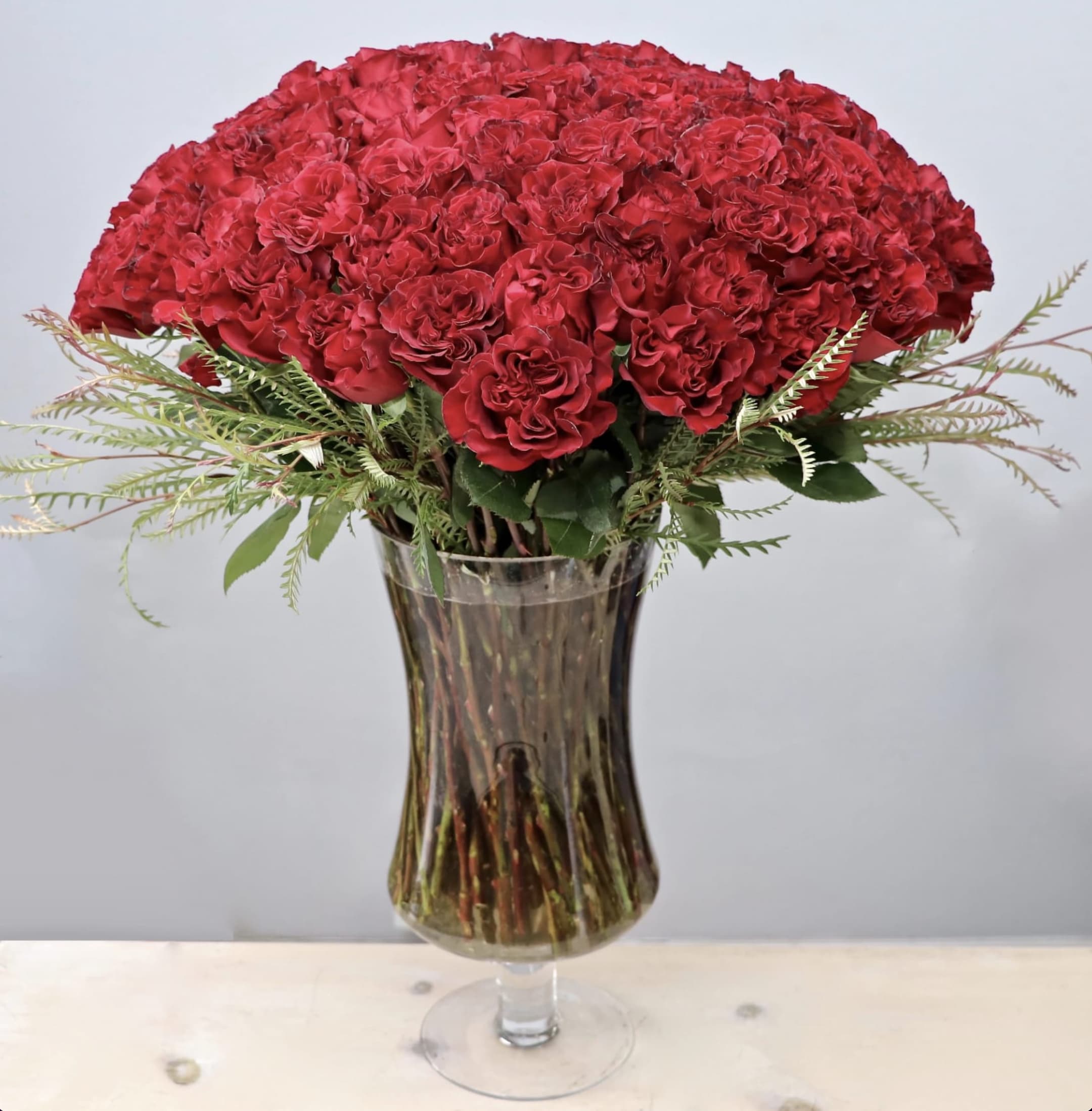 Large arrangement of red carnations in a tall clear glass vase