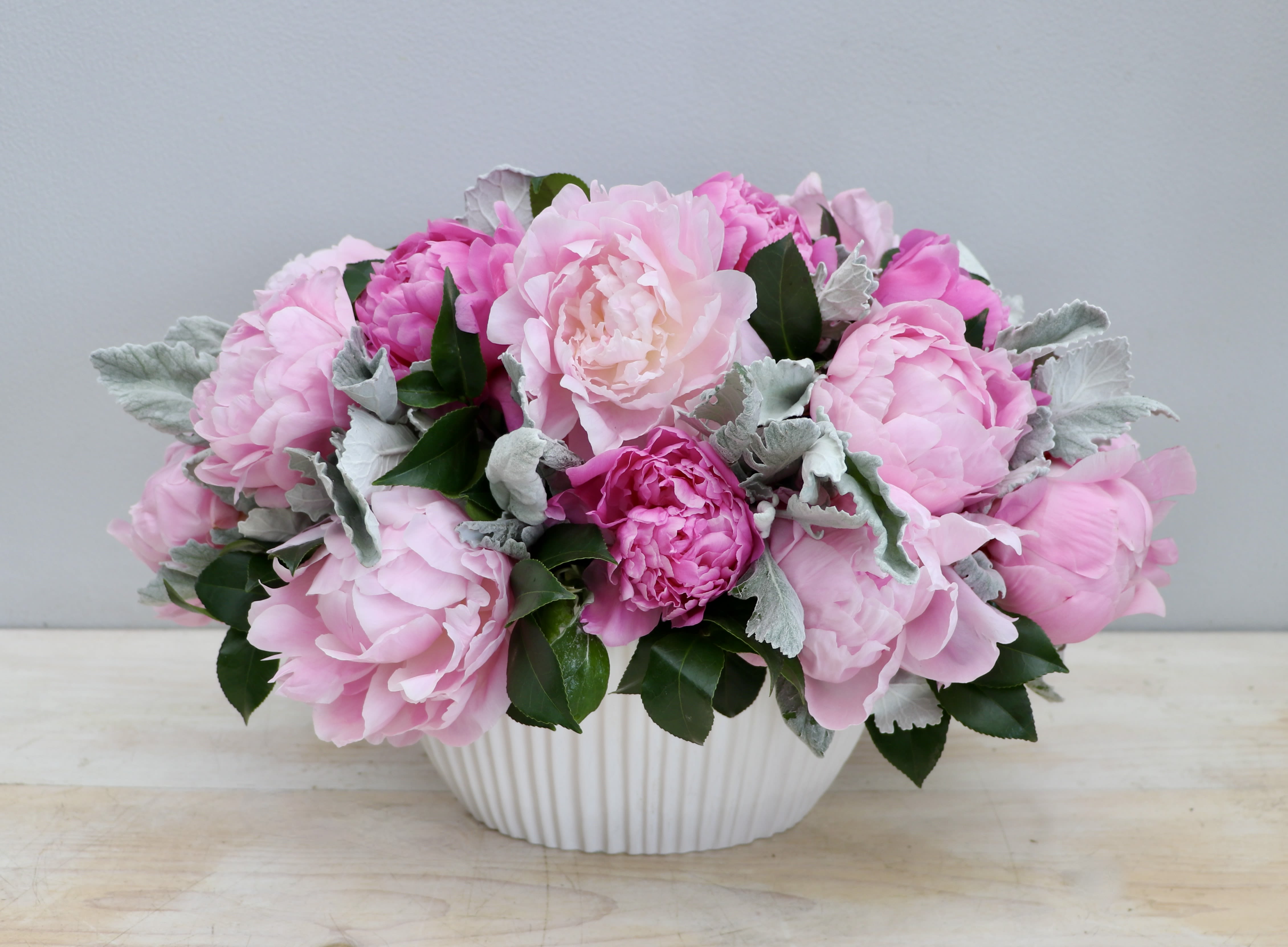 Low arrangement of pink peonies in a white ceramic bowl