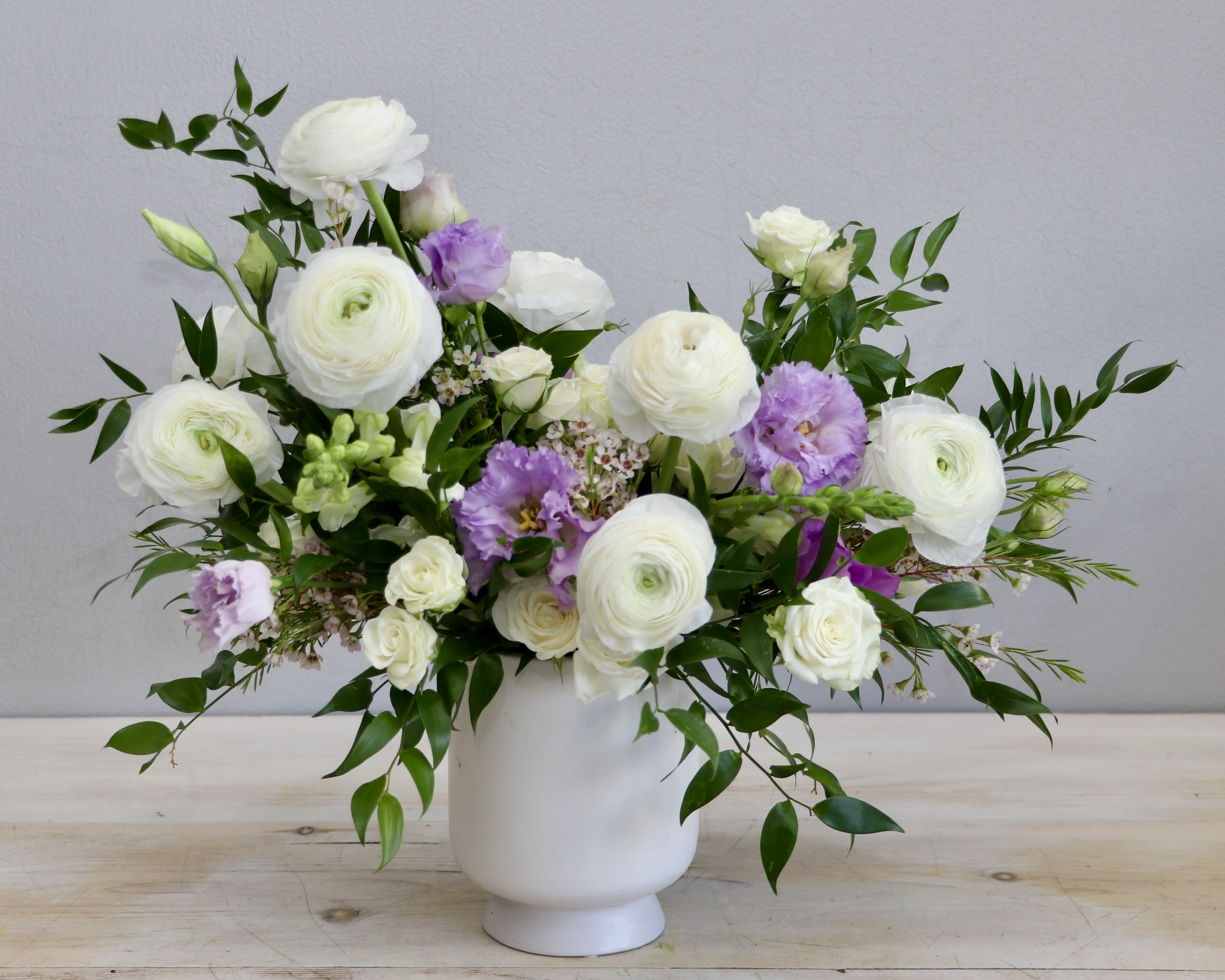 White and light purple flower arrangement in a matte white vase
