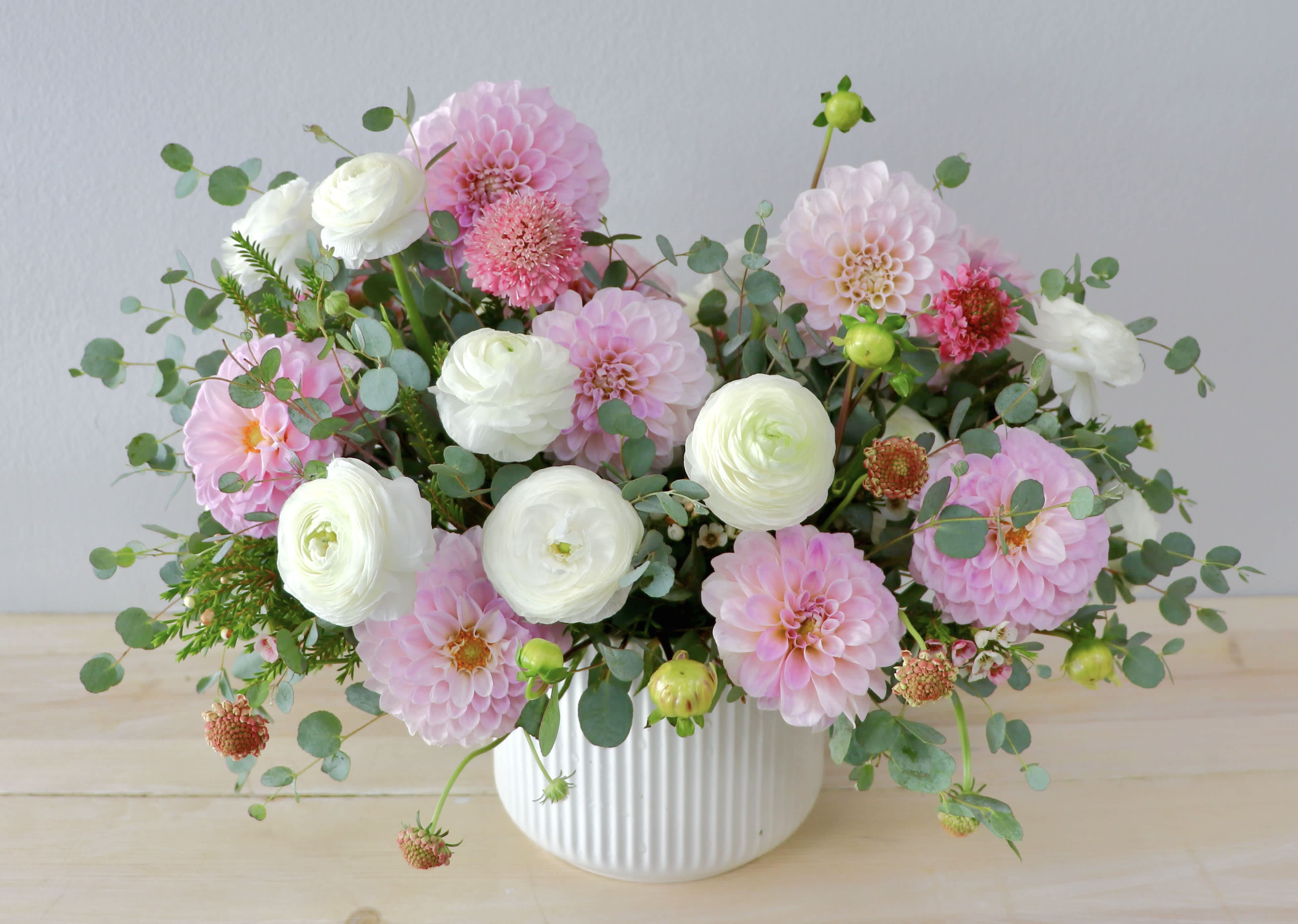 Pink and white flowers arranged in a white ribbed vase