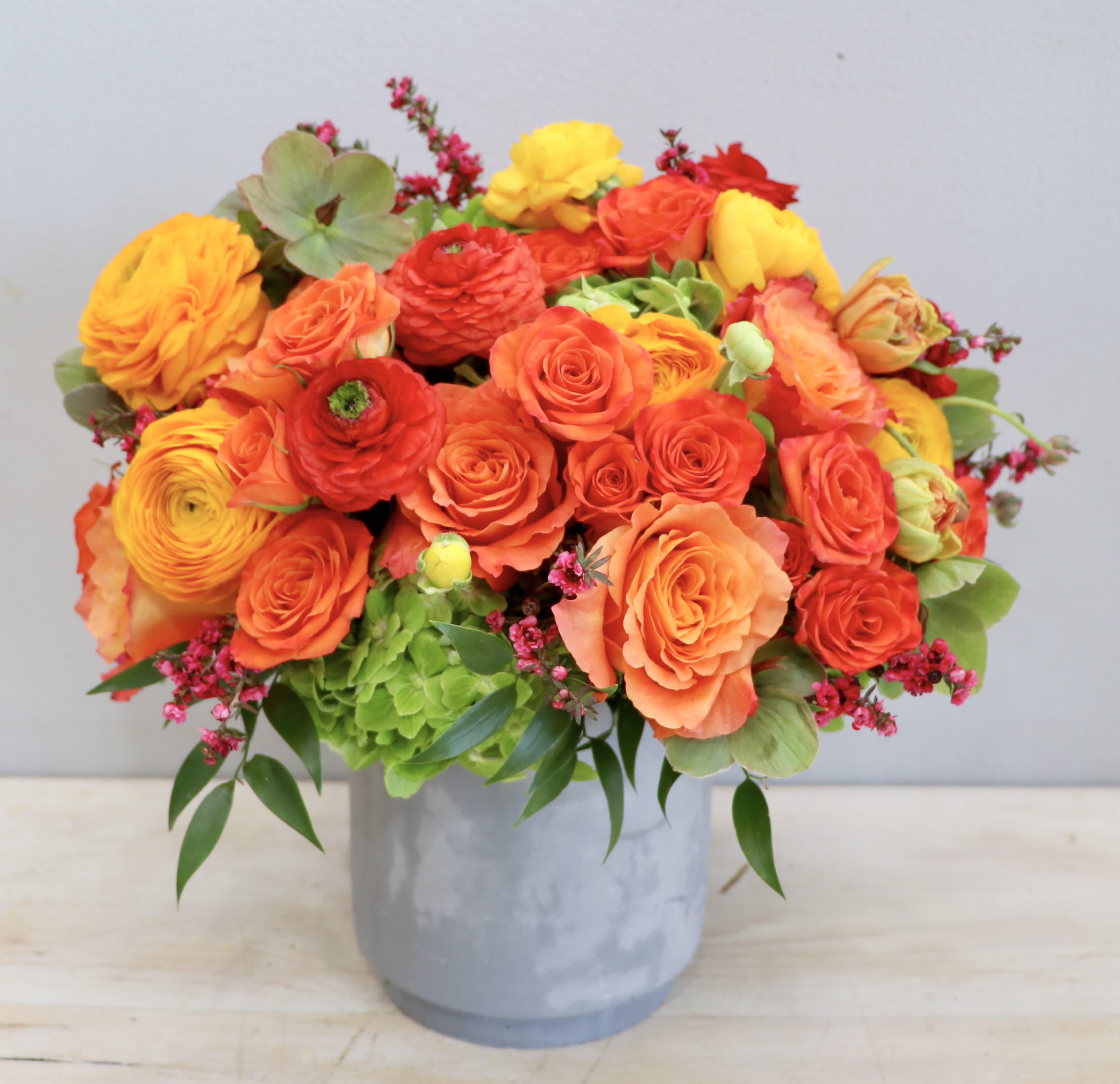 Bright orange and yellow flower arrangement in a gray vase