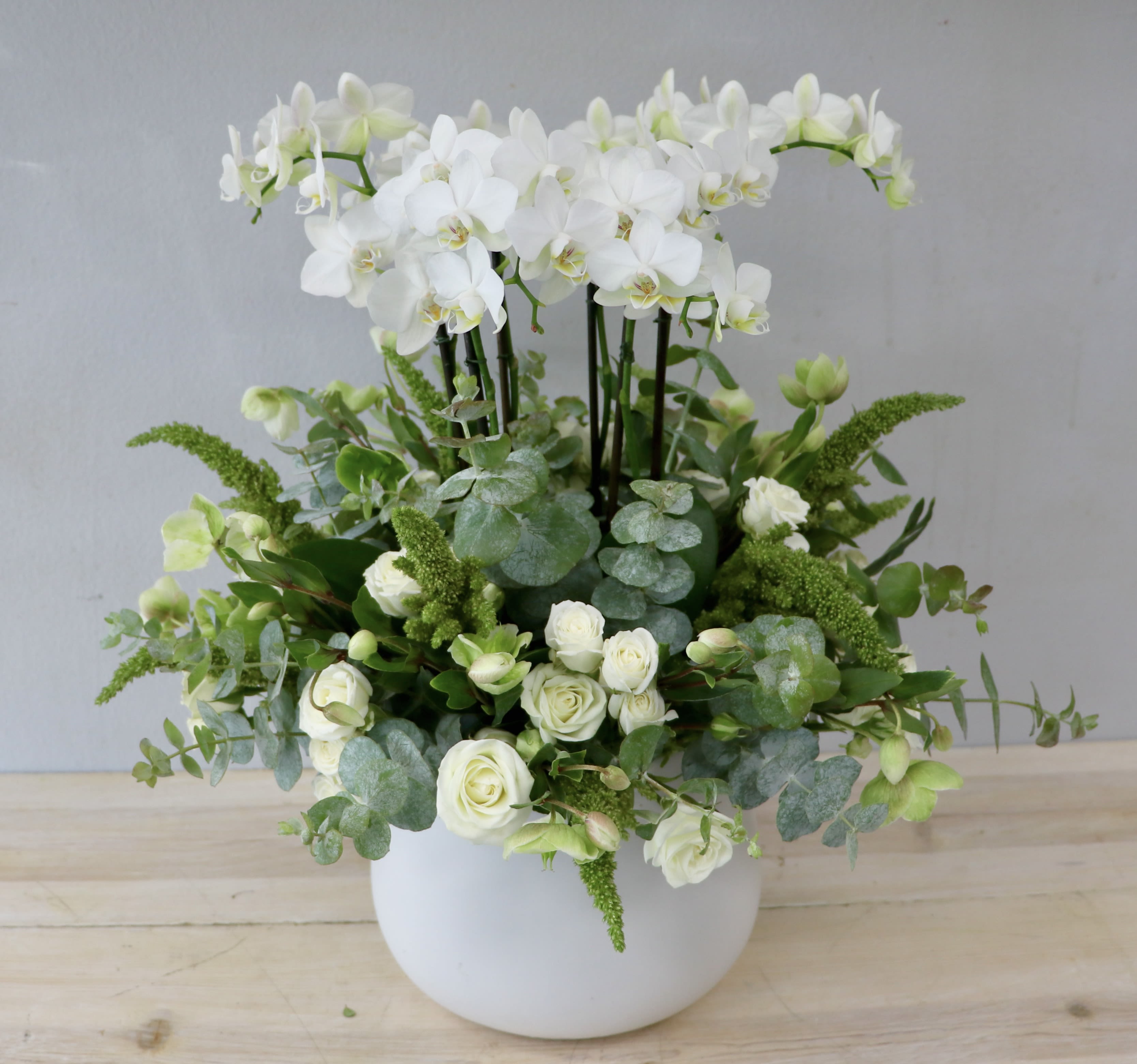 White orchids and roses arranged in a white vase