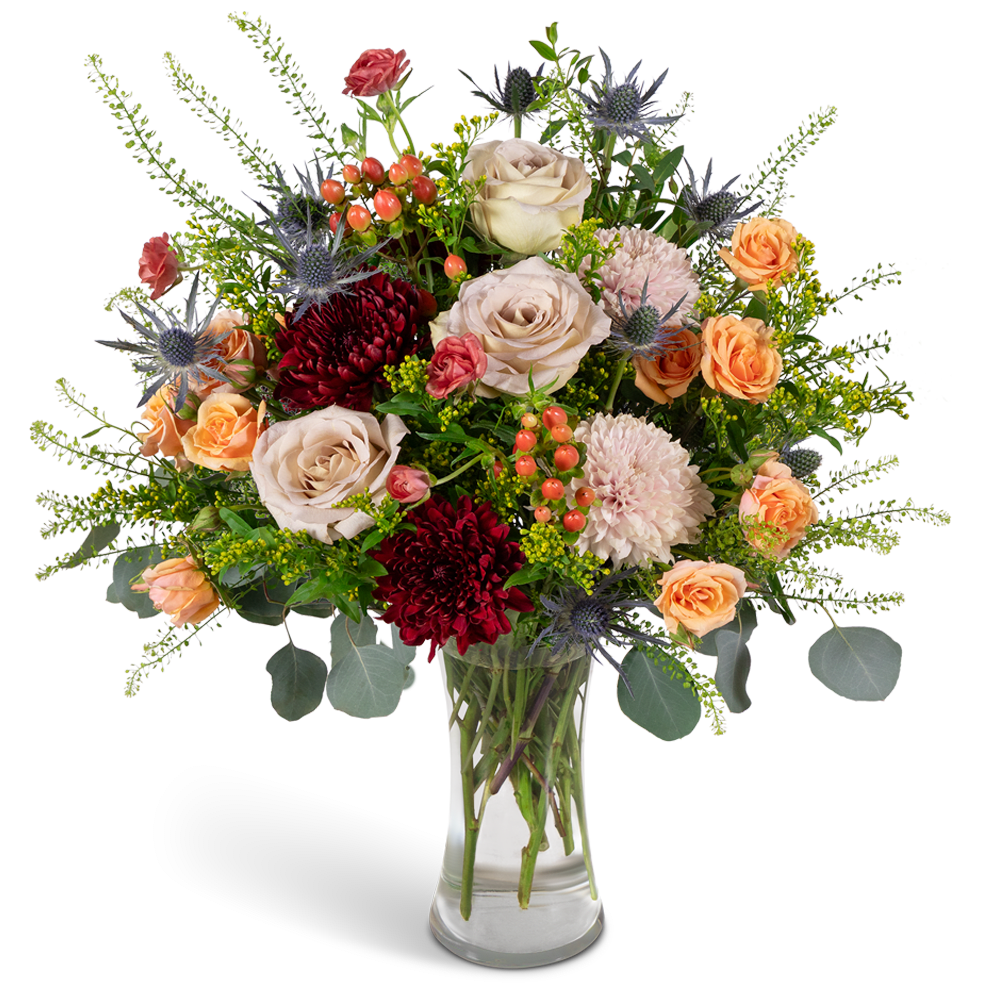 Mixed bouquet of roses, chrysanthemums, and thistle in a clear glass vase