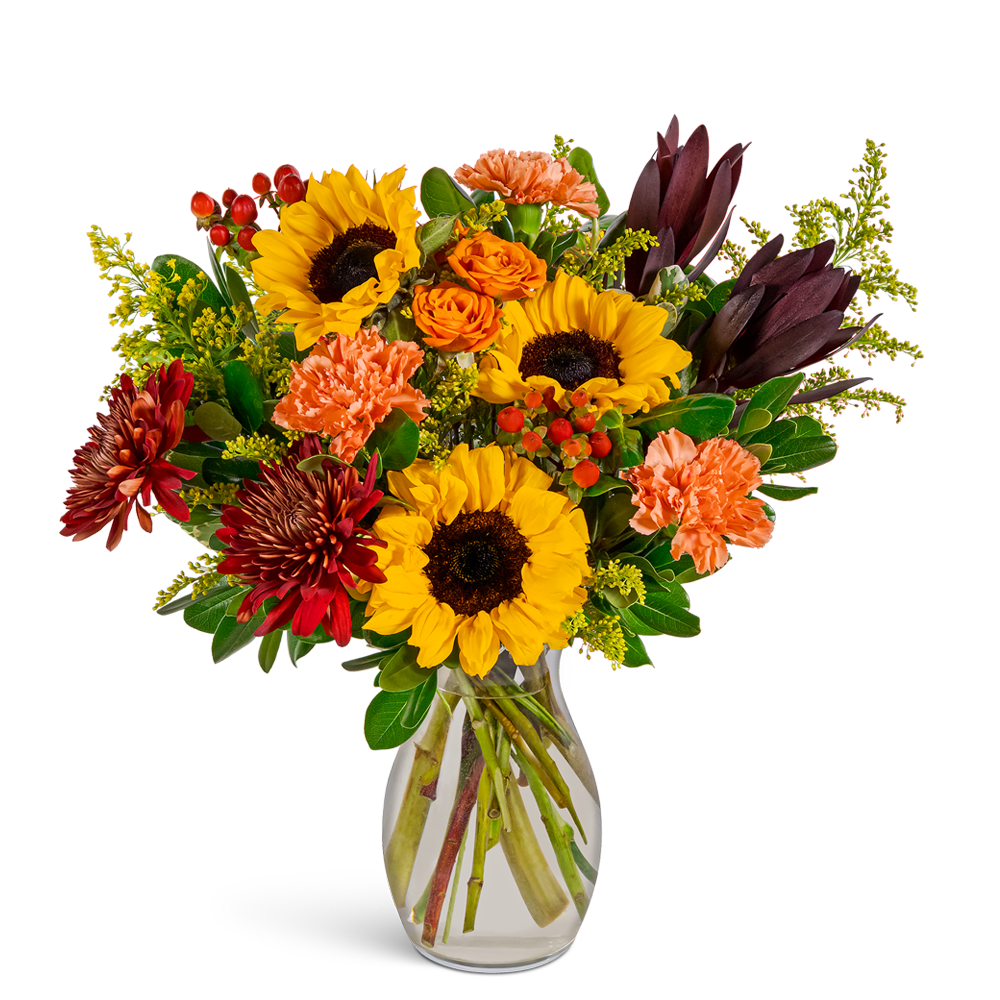 Bouquet of sunflowers, orange roses, and carnations in a clear glass vase