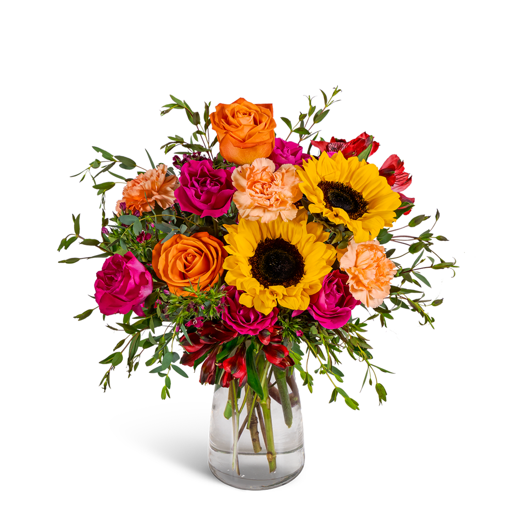 Bouquet of orange and pink flowers with sunflowers in a clear glass vase