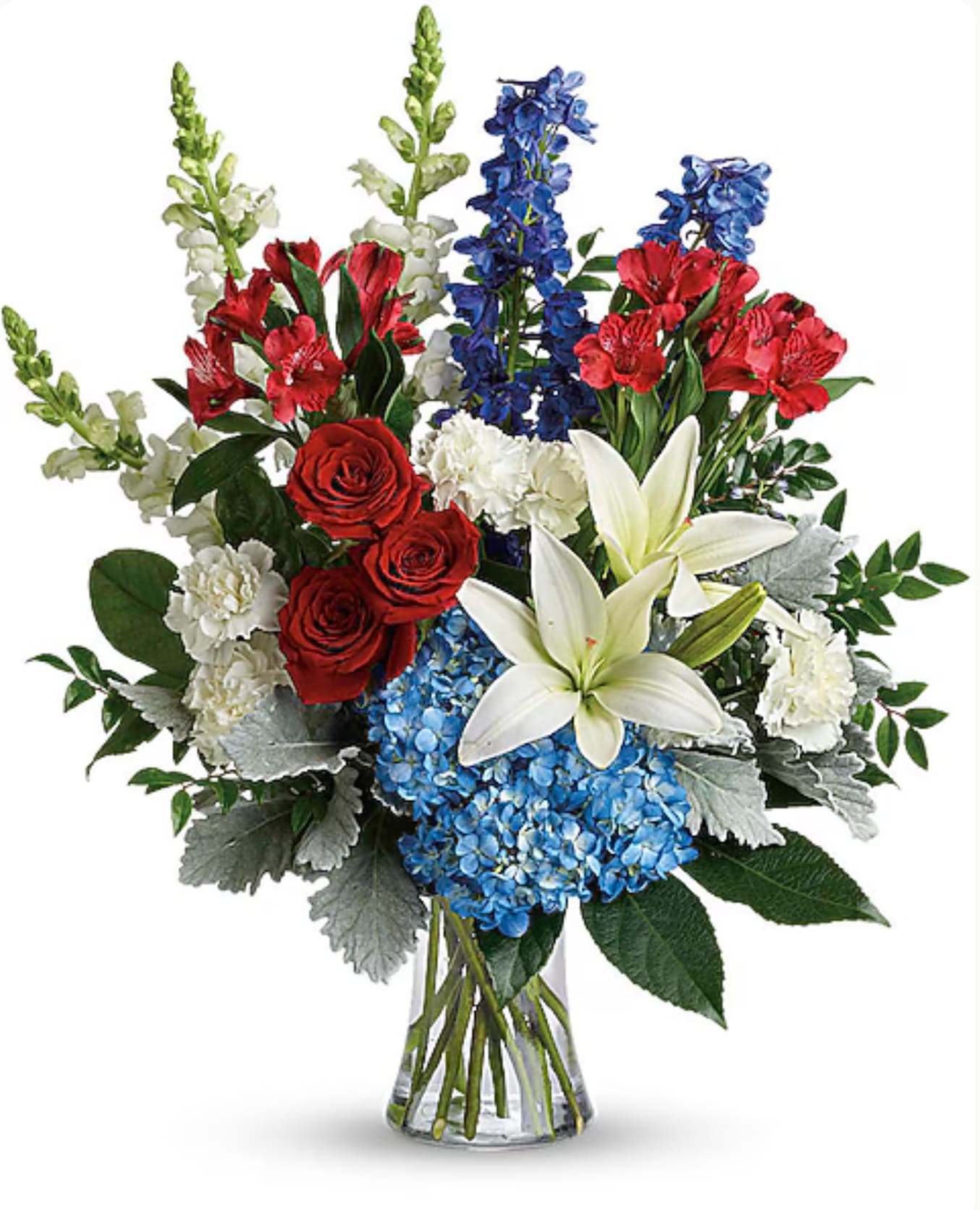 Mixed bouquet of red roses, white lilies, blue hydrangeas, and red blooms in a glass vase