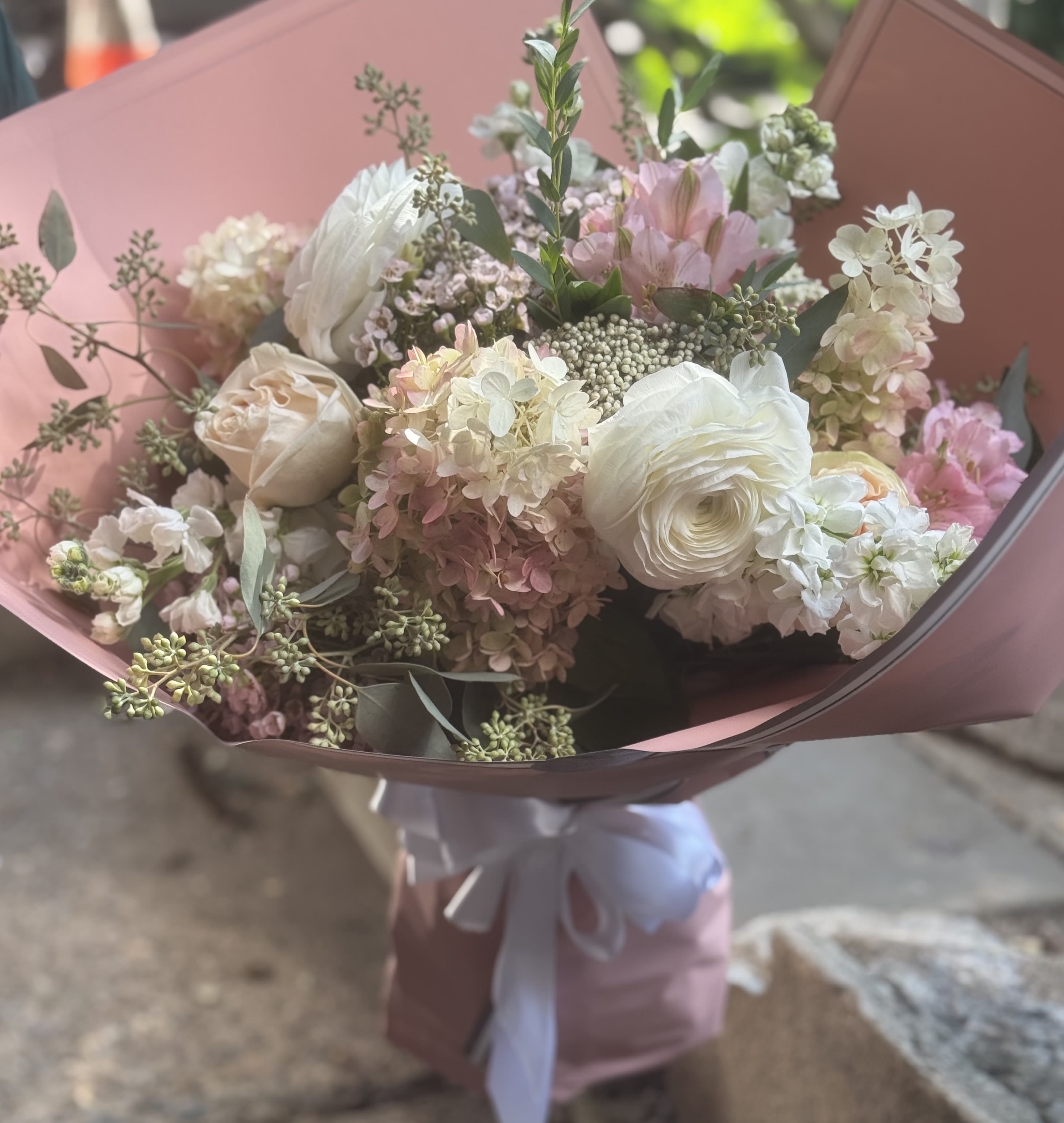 Bouquet of white and blush flowers wrapped in pink paper
