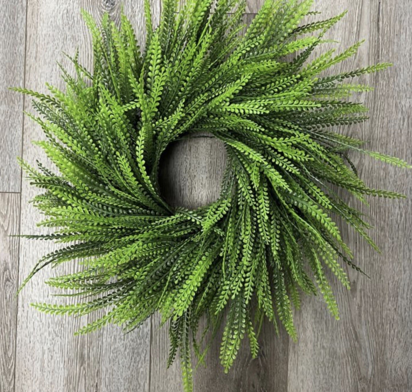 22” Premium Beaded Grass Wreath - A lush, feathery ring of beaded grass brings effortless greenery to any room - perfect as a spring accent, a housewarming gift, or a "just because" surprise. This circular wreath reads fresh and natural with bright and dark green tones layered into a full, slightly wild silhouette that feels casual rather than formal, so the person you're thinking of will enjoy it year-round.  Made from dense, narrow silk greenery with a soft, airy texture, the wreath's layered construction creates depth and movement from every angle. The faux beaded grass is arranged into a generous, rustic ring that looks convincingly botanical without shedding or upkeep. Size and exact dimensions are preserved as shown in the product images for easy placement on doors, over mantels, or as a centerpiece accent.  Ideal for summer porches, spring mantel displays, or to warm up a new home, this wreath offers instant greenery without care-no watering or trimming required. Order with confidence for someone who appreciates natural texture and low-maintenance style; it arrives ready to hang and brings a quiet, lived-in charm to the space.