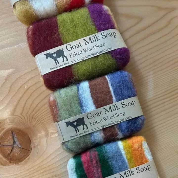 Stack of multicolored felted wool soap bars on a wooden surface