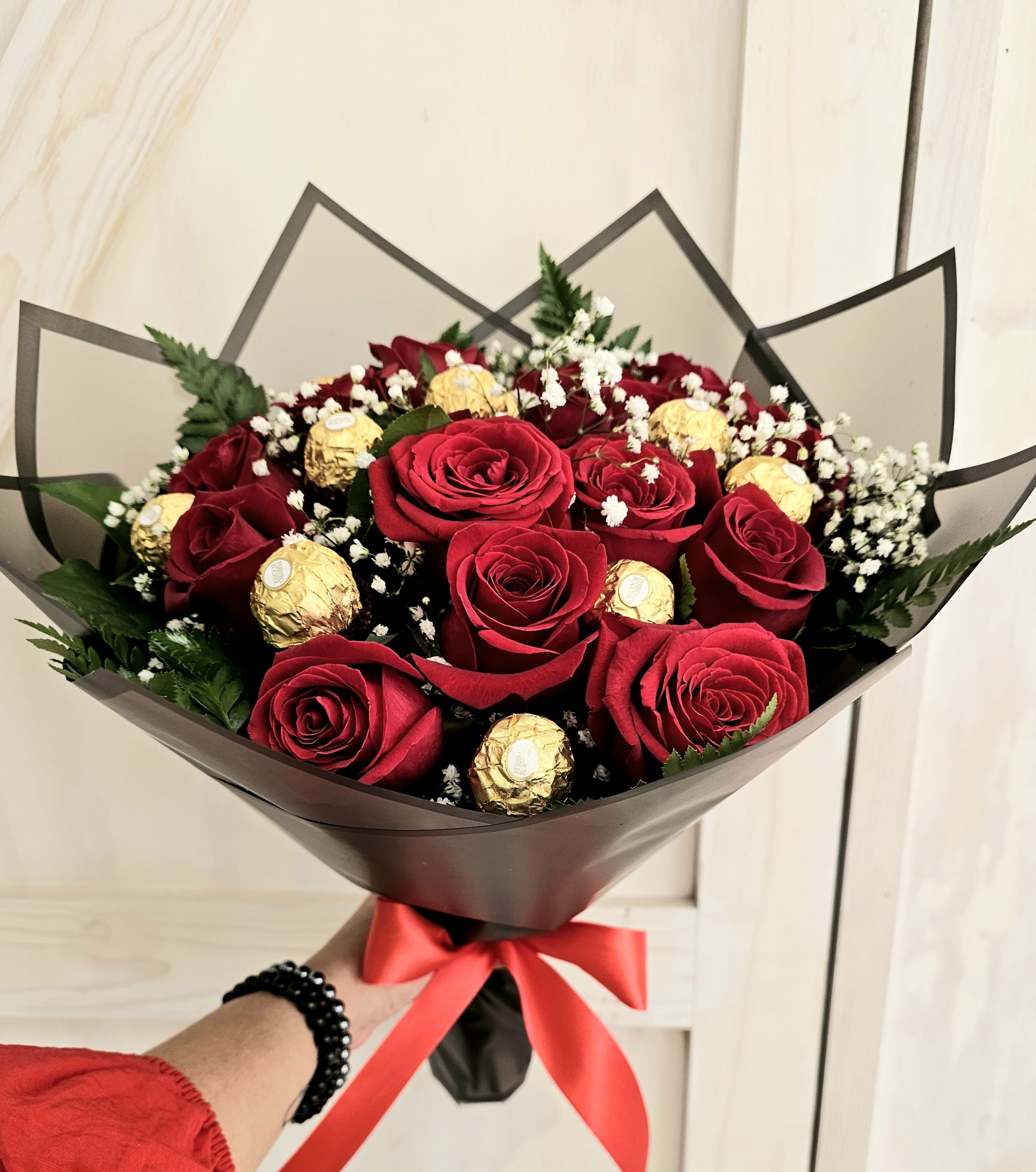 Bouquet of red roses with gold-wrapped chocolates and baby's breath