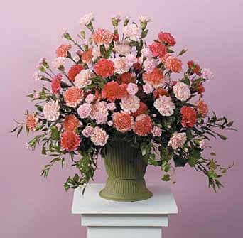 Large pink and coral carnation arrangement in a green vase