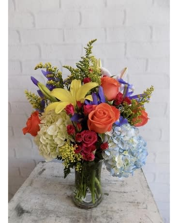 Colorful bouquet of roses, lilies, and hydrangeas in a glass vase