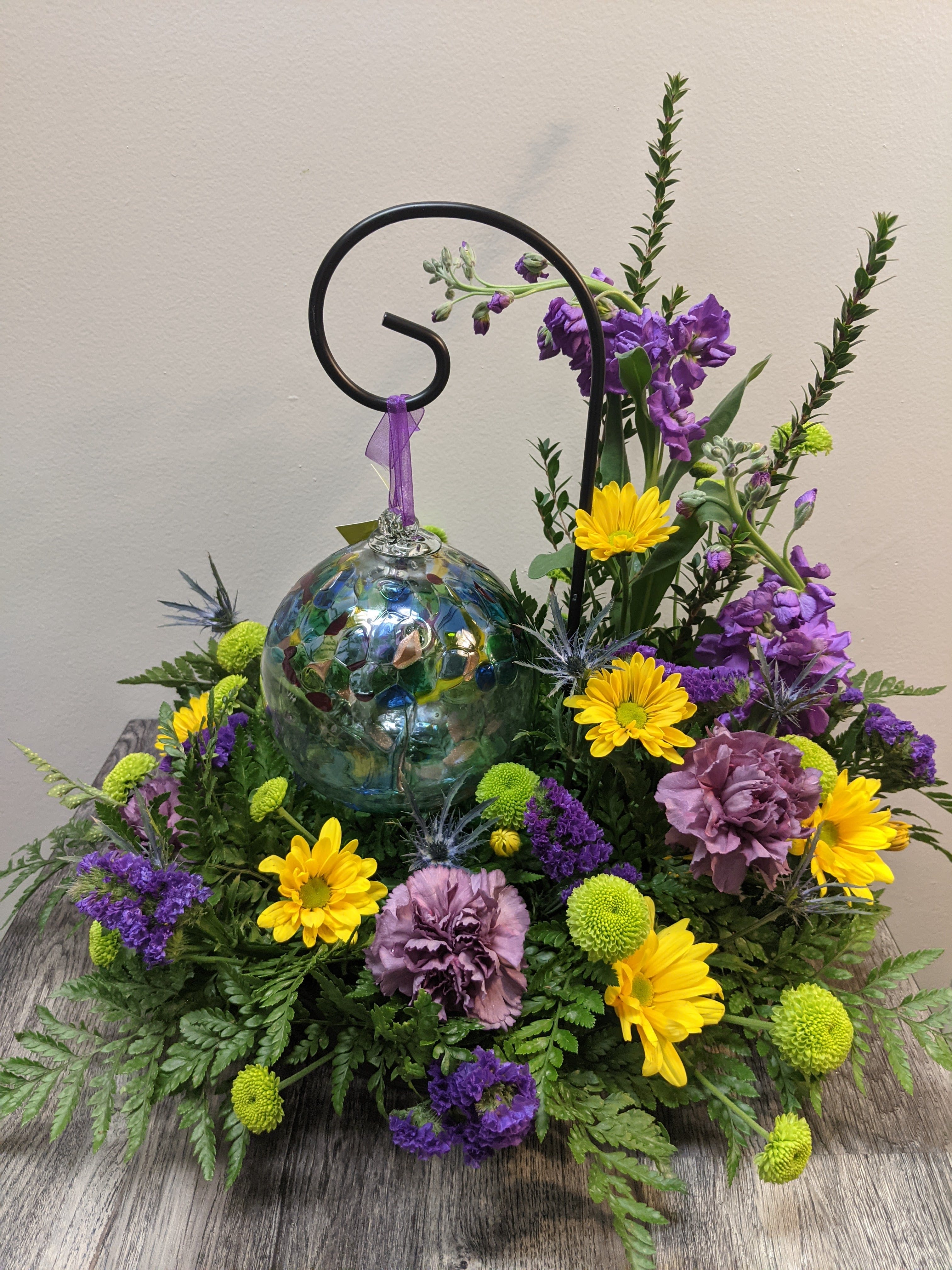Purple and yellow floral arrangement with a glass ornament centerpiece