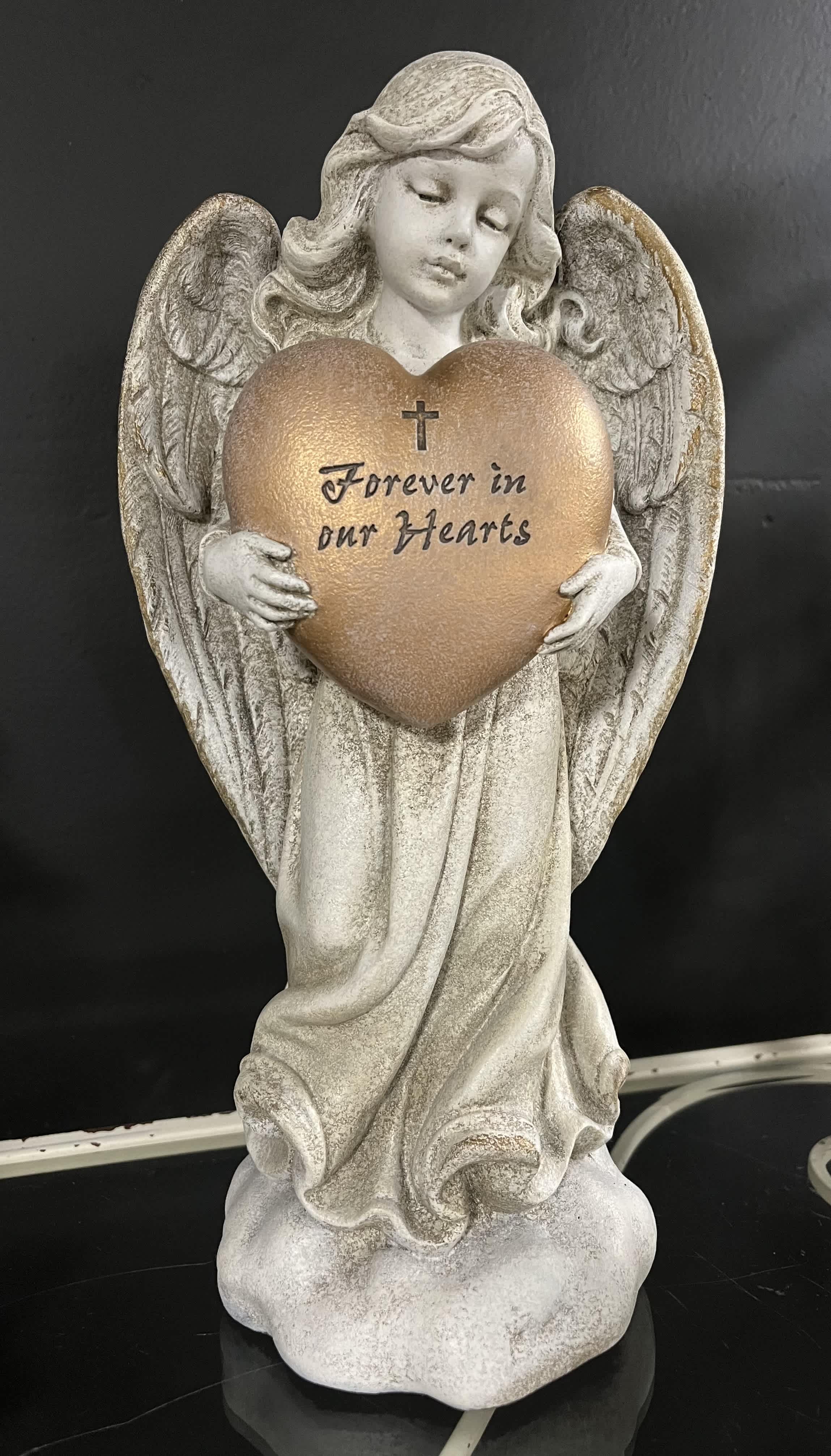 Angel figurine holding a heart plaque with the words Forever in our Hearts