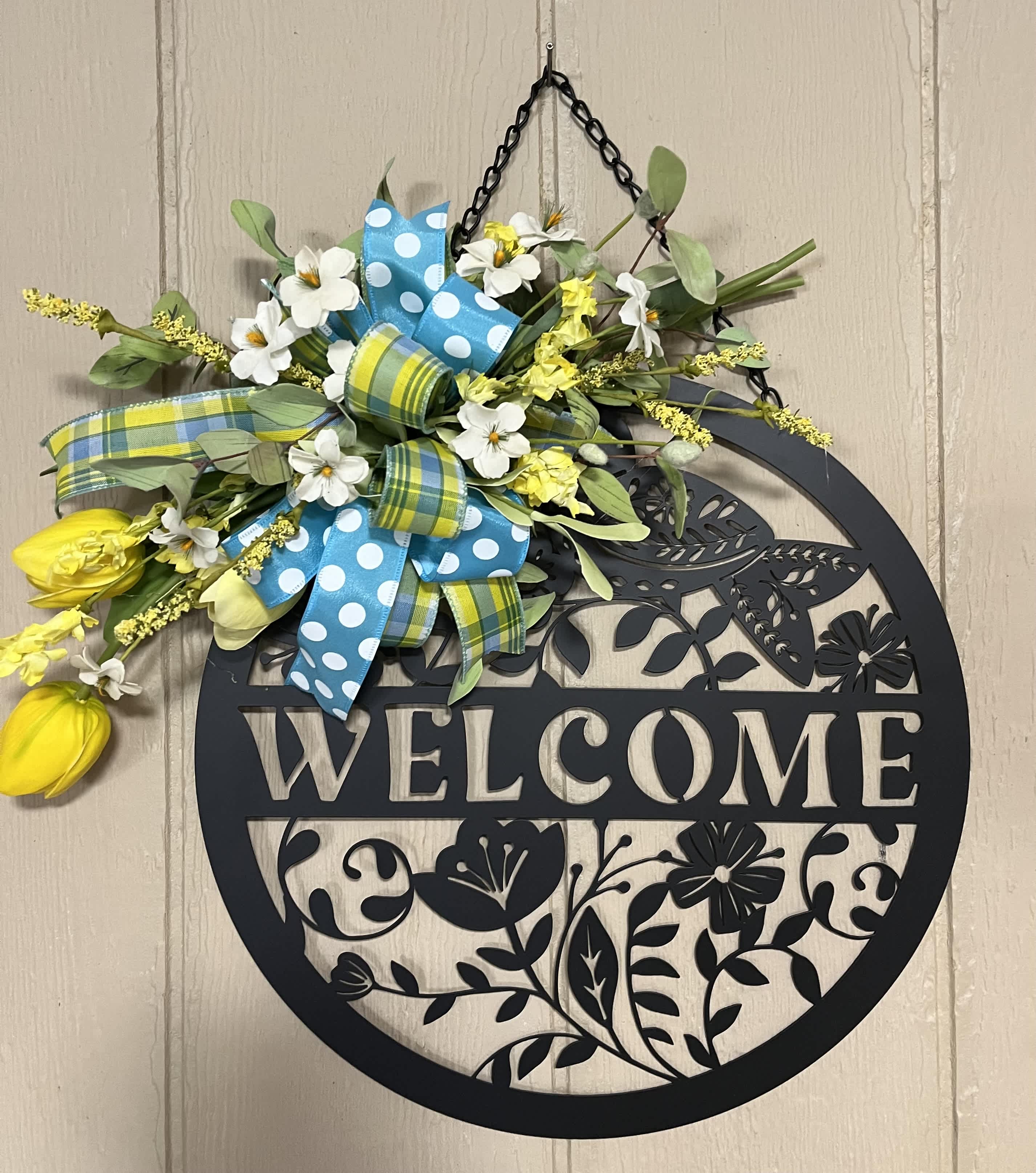 Floral welcome sign with yellow and white flowers and blue ribbons