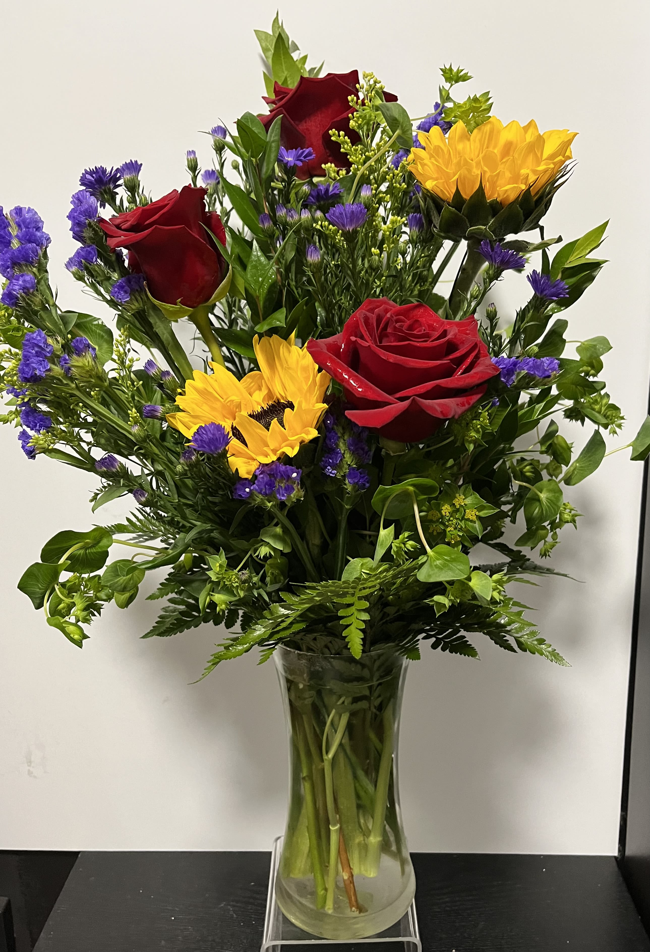 Bouquet of red roses and yellow sunflowers in a clear glass vase