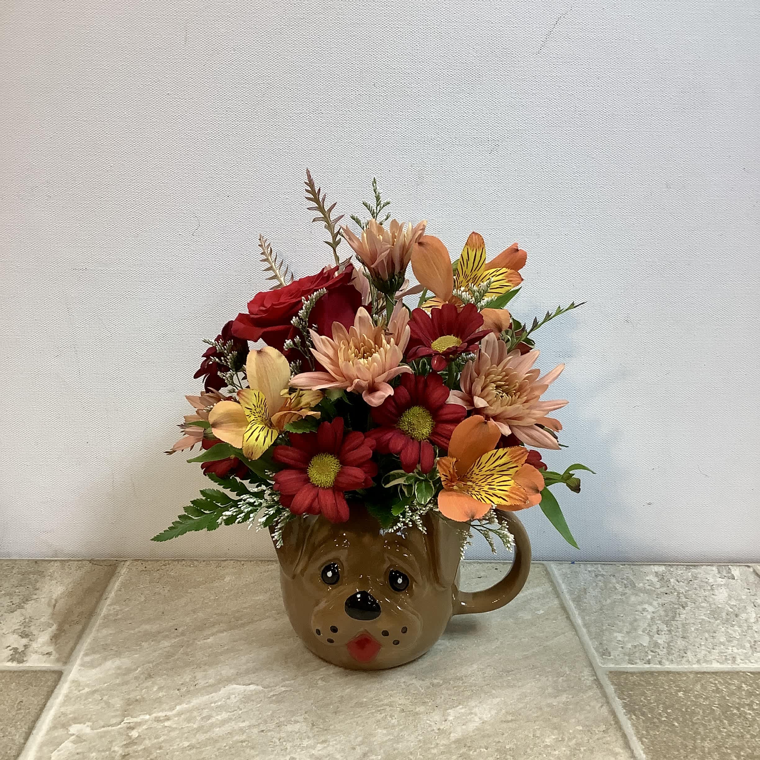Mixed bouquet in a brown bear mug with red, peach, and yellow flowers