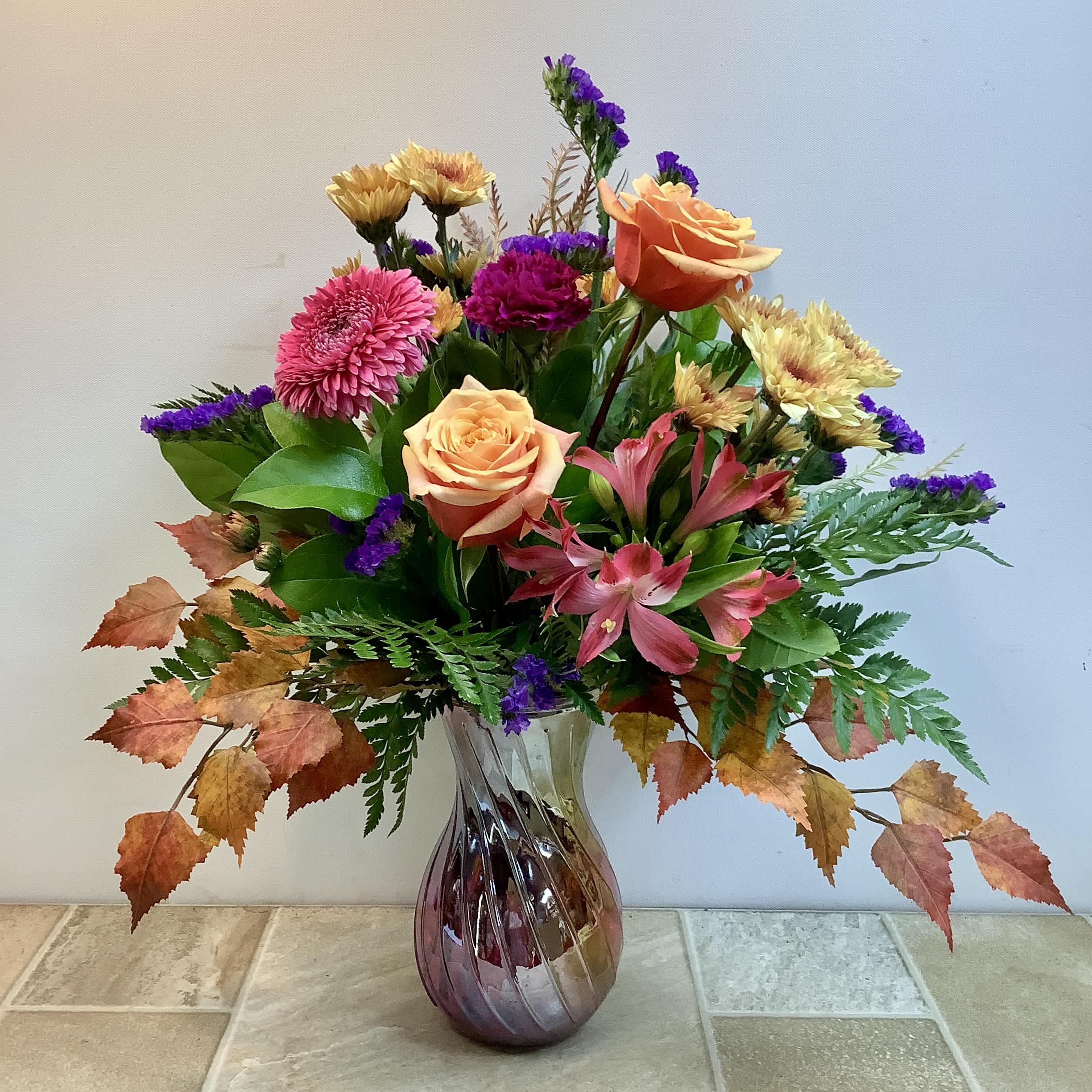Mixed bouquet of roses, chrysanthemums, and alstroemeria in a glass vase