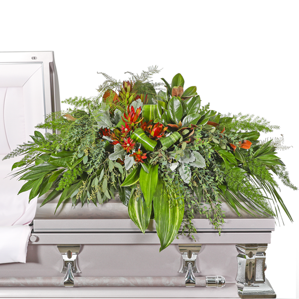 Large floral casket spray with red blooms and mixed greenery on a silver casket