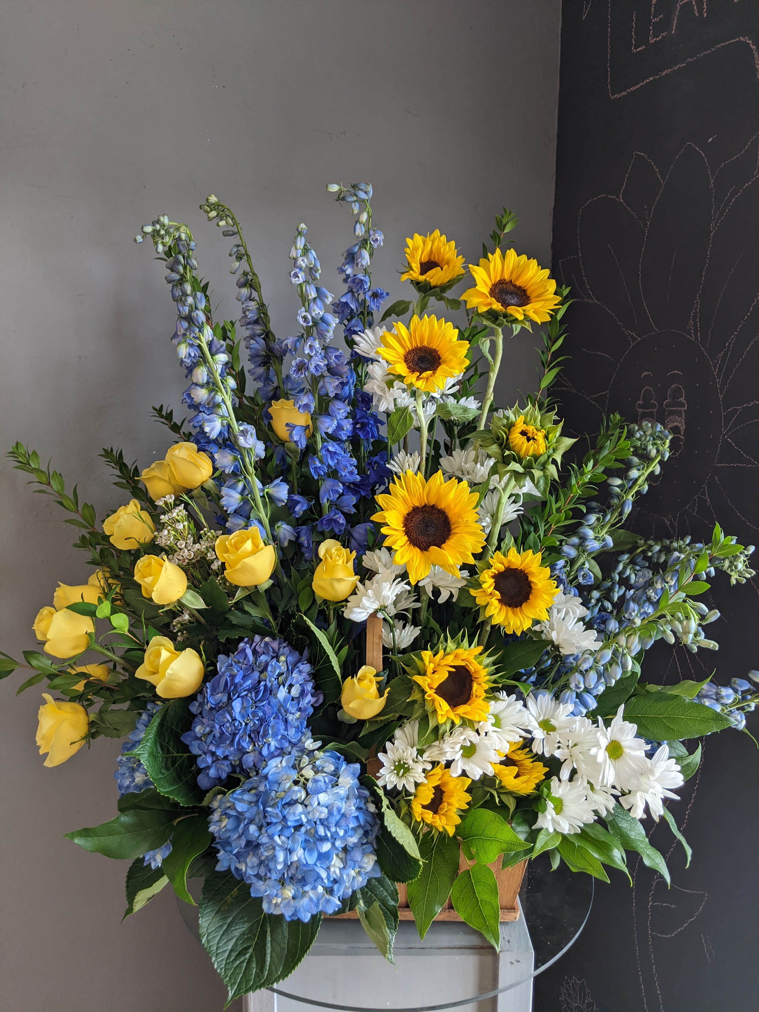 Mixed bouquet with sunflowers, yellow roses, blue hydrangeas, and white daisies
