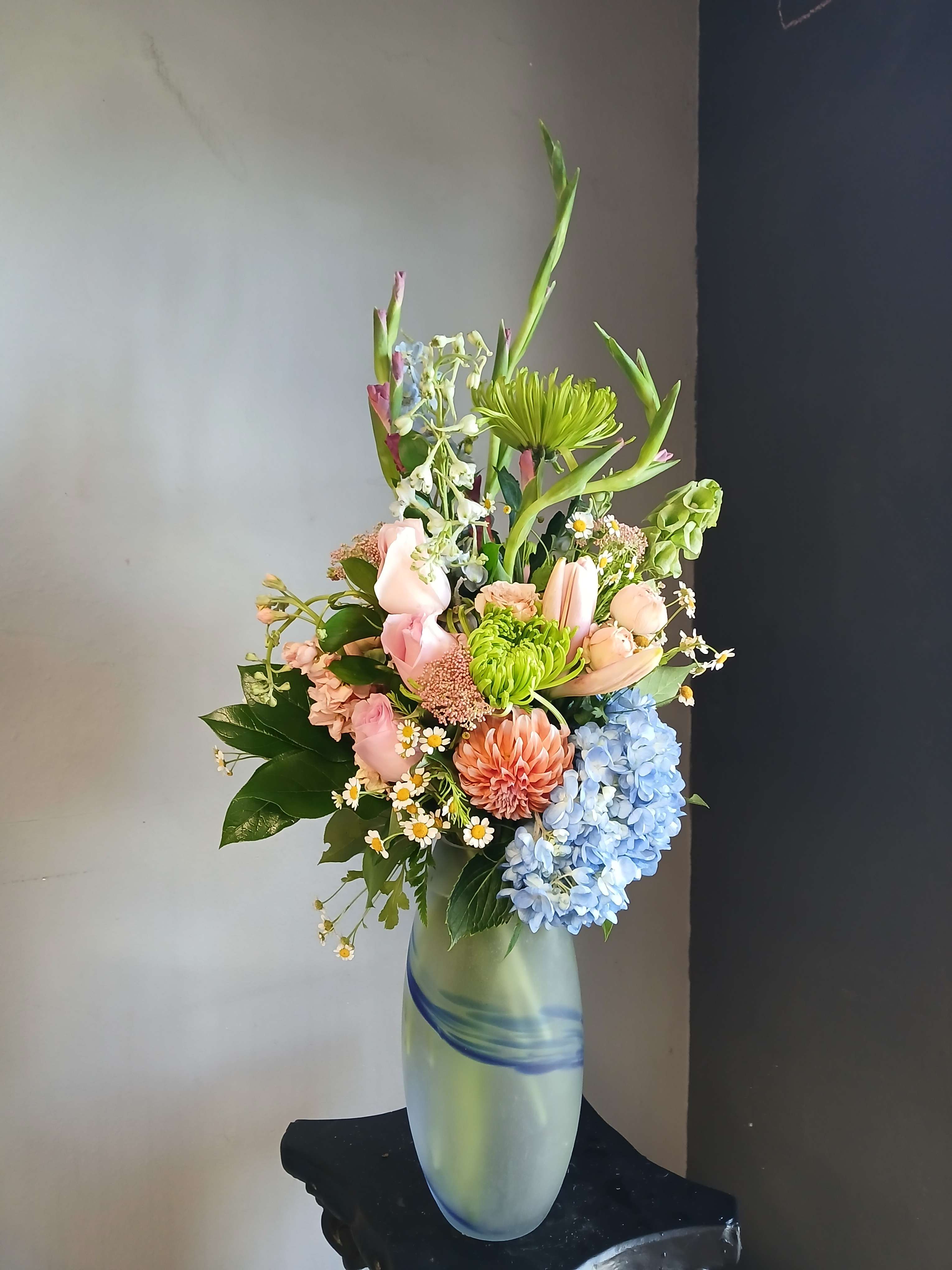 Mixed pastel bouquet in a tall frosted glass vase