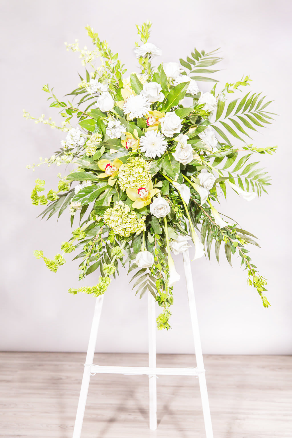 Tall white floral standing spray on a white easel