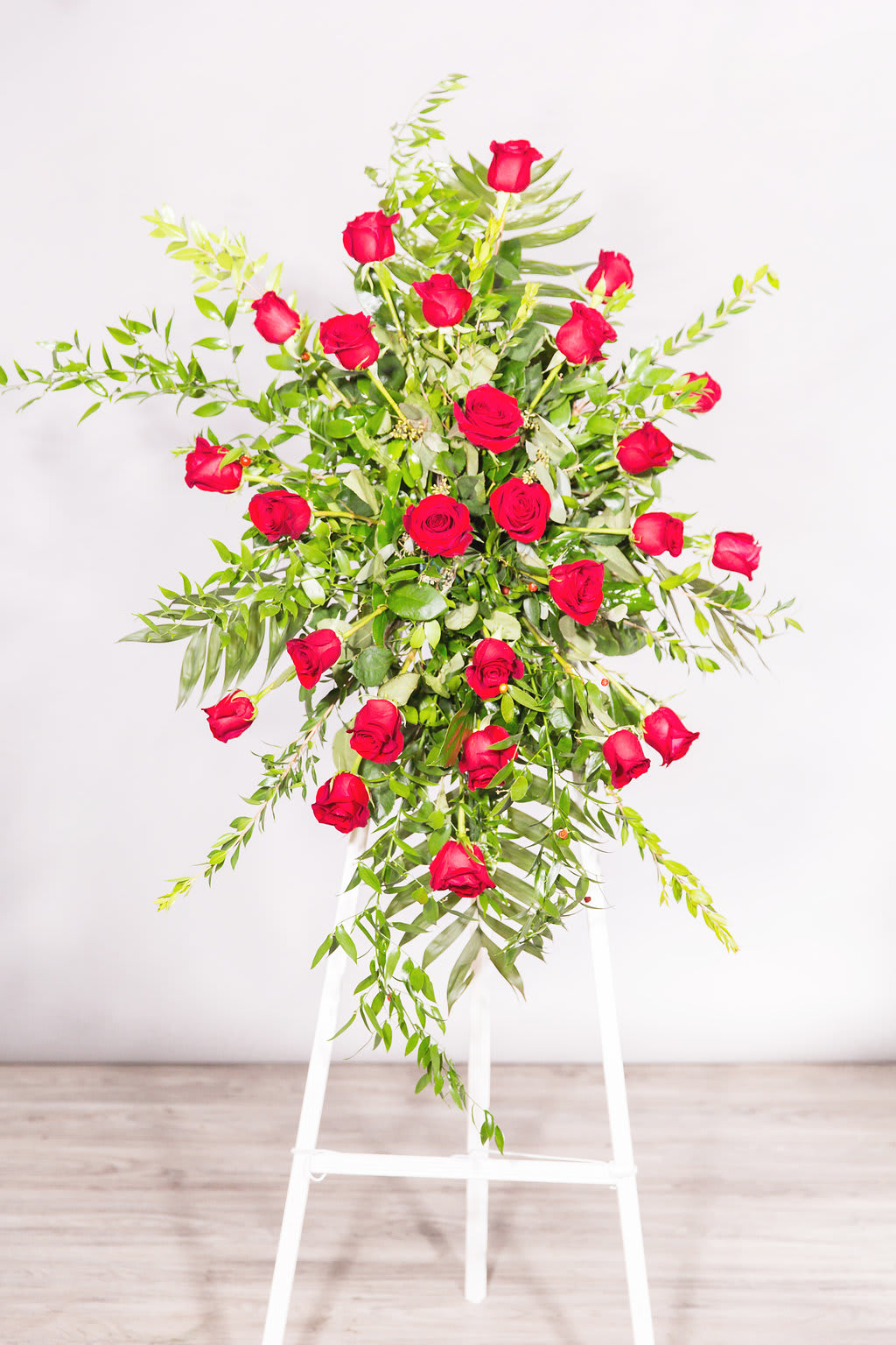 Tall arrangement of red roses on a white stand