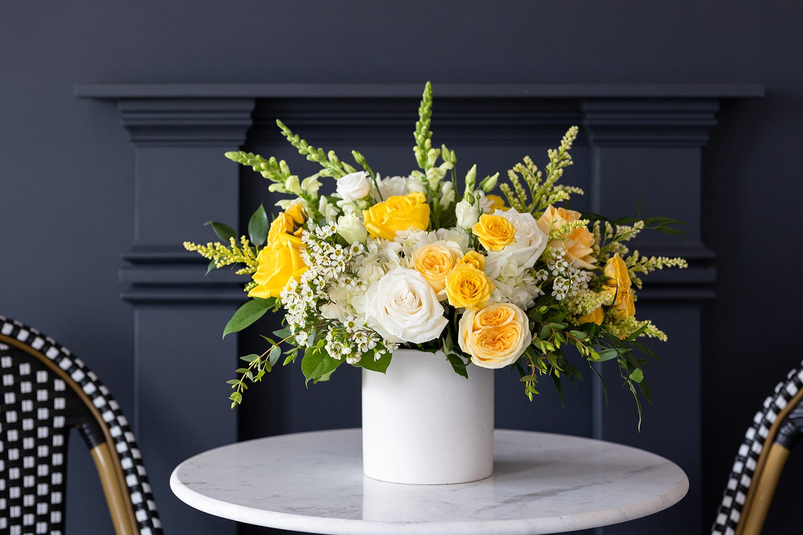 Yellow and white roses arranged in a white vase