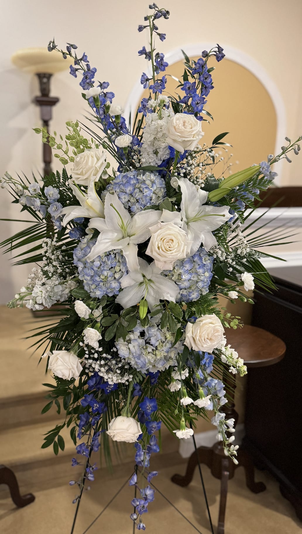 Tall blue and white floral spray with roses, lilies, and hydrangeas