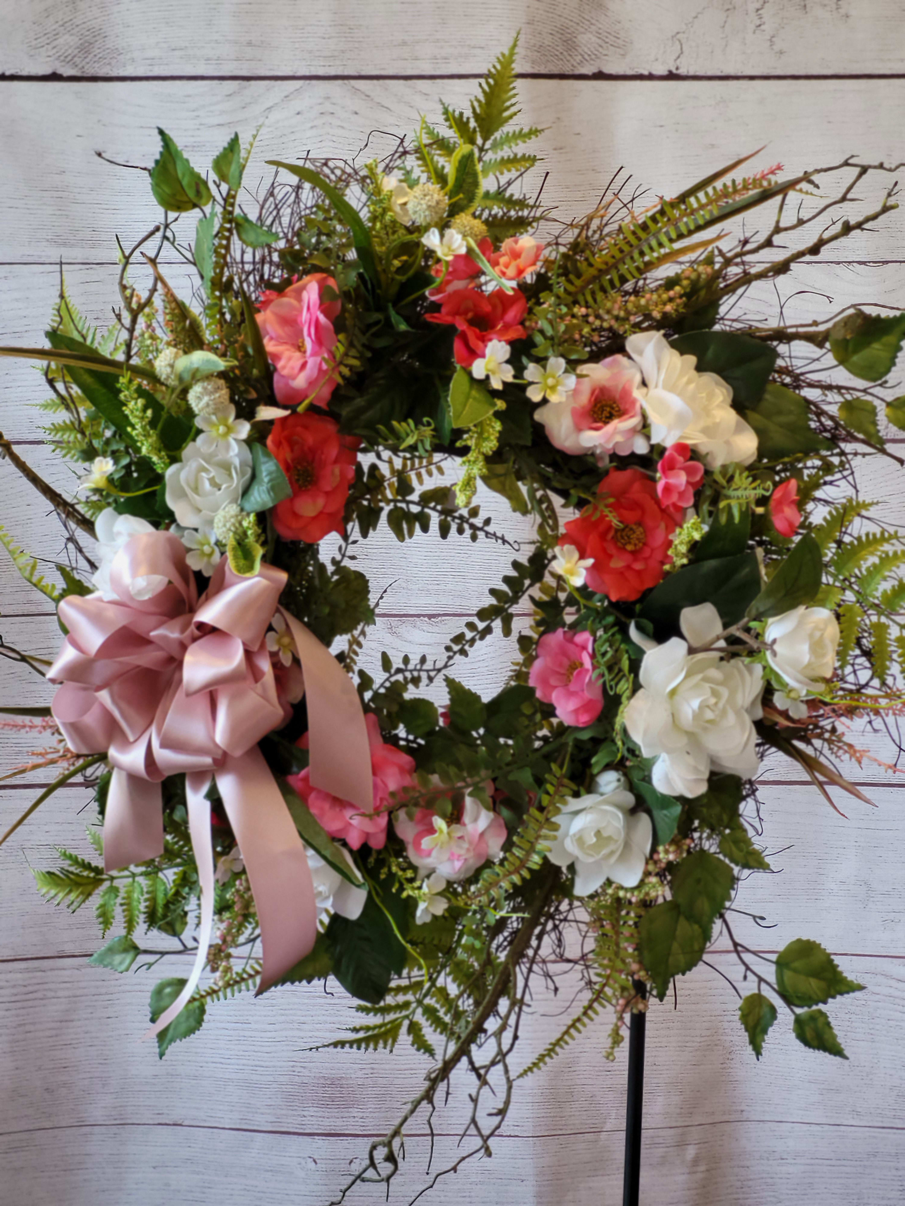 Heart-shaped floral wreath with pink and white flowers and a satin bow