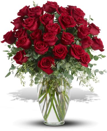Red roses arranged in a clear glass vase with greenery