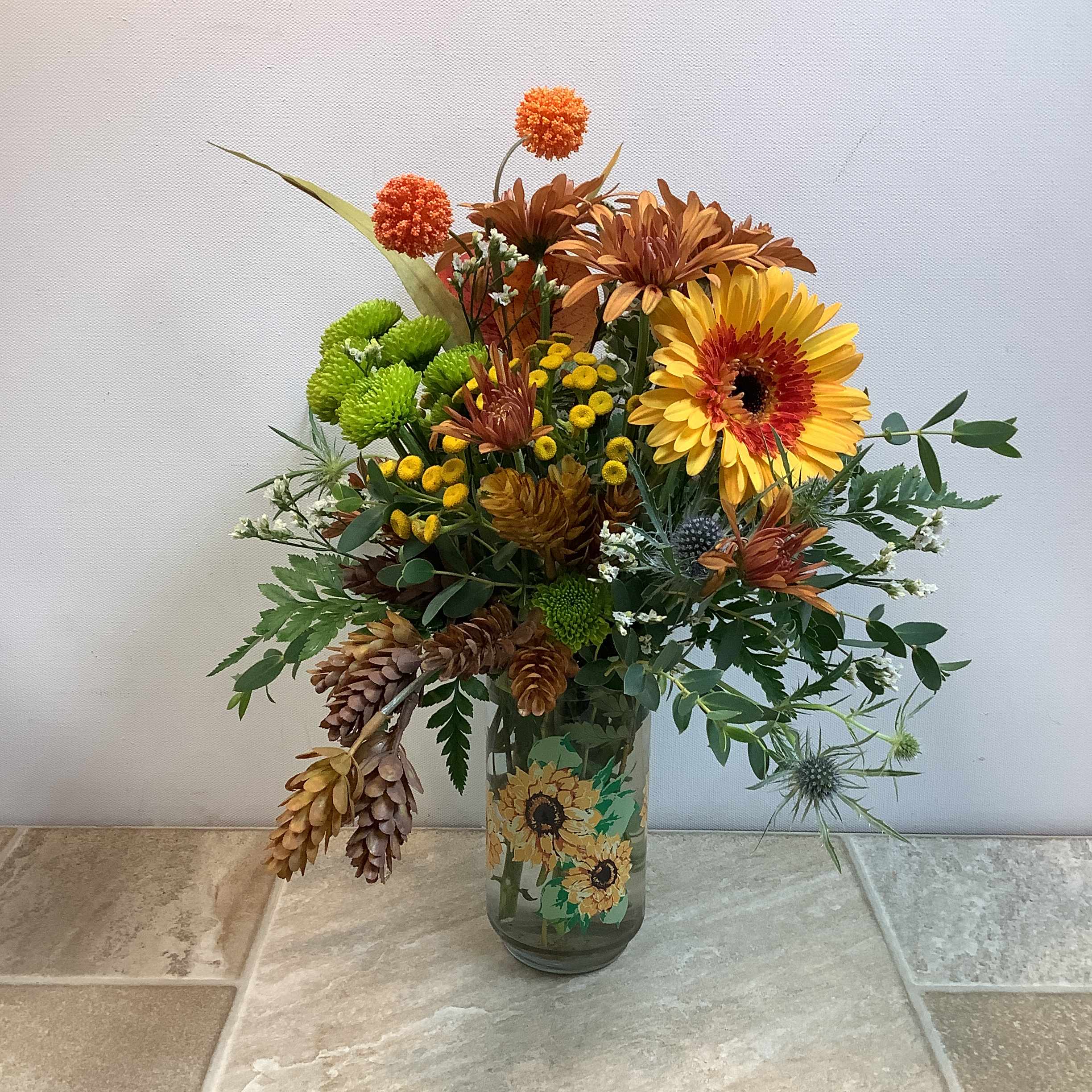 Mixed autumn bouquet in a glass vase with yellow and orange blooms