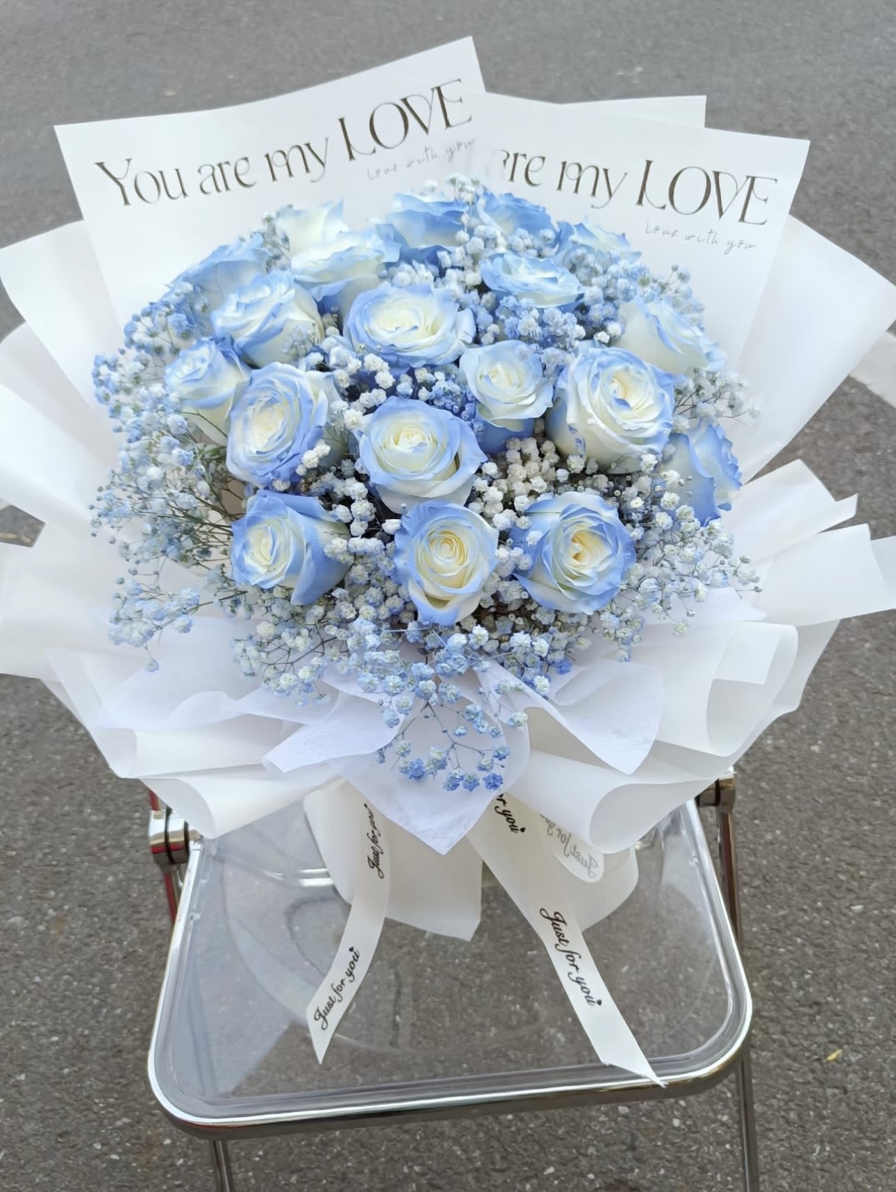 Blue and white rose bouquet with baby's breath in white wrap