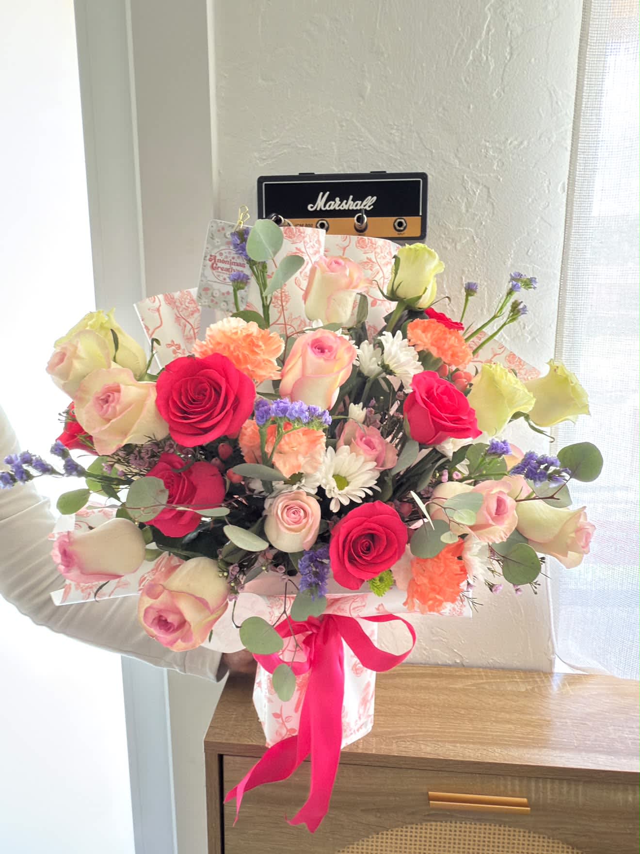 Mixed bouquet of pink and cream roses with carnations and daisies in pink wrap