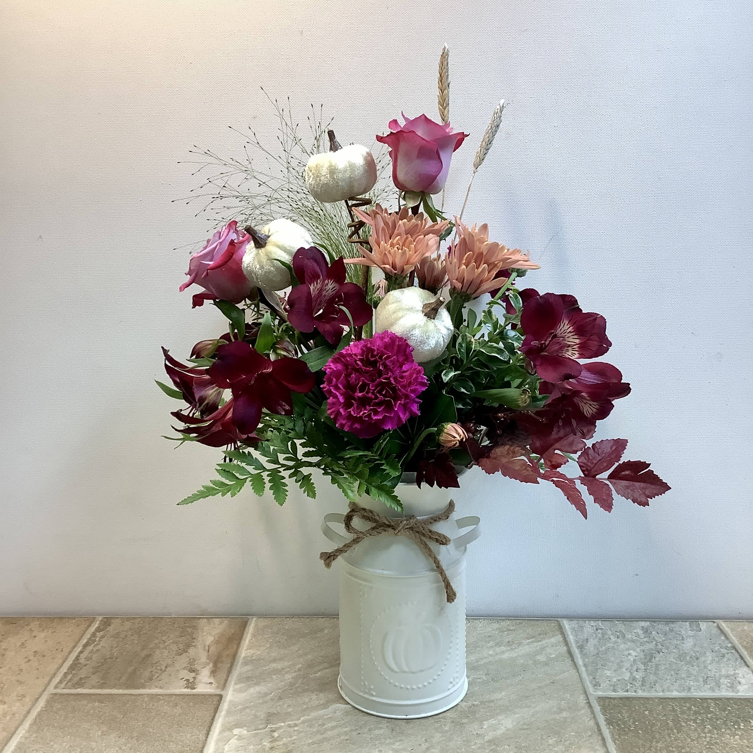 Mixed bouquet with pink roses, burgundy flowers, and white pumpkins in a white vase