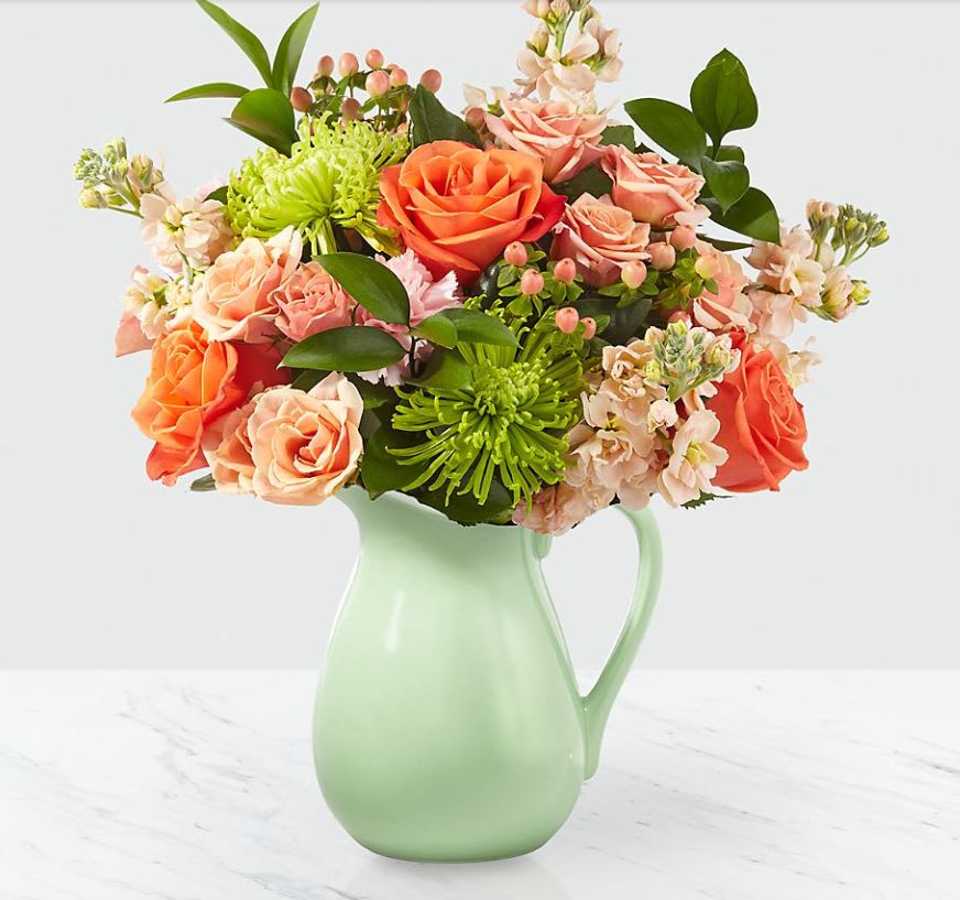 Pop of Color - Warmer weather calls for blooms that are radiant, happy and oh so vibrant! Our Pop of Color™ pick is the perfect combination of bursting flowers and fun texture, all in an aqua pitcher vase. This handcrafted bouquet comes with a collection of roses, stock, spray roses and Fuji mums!