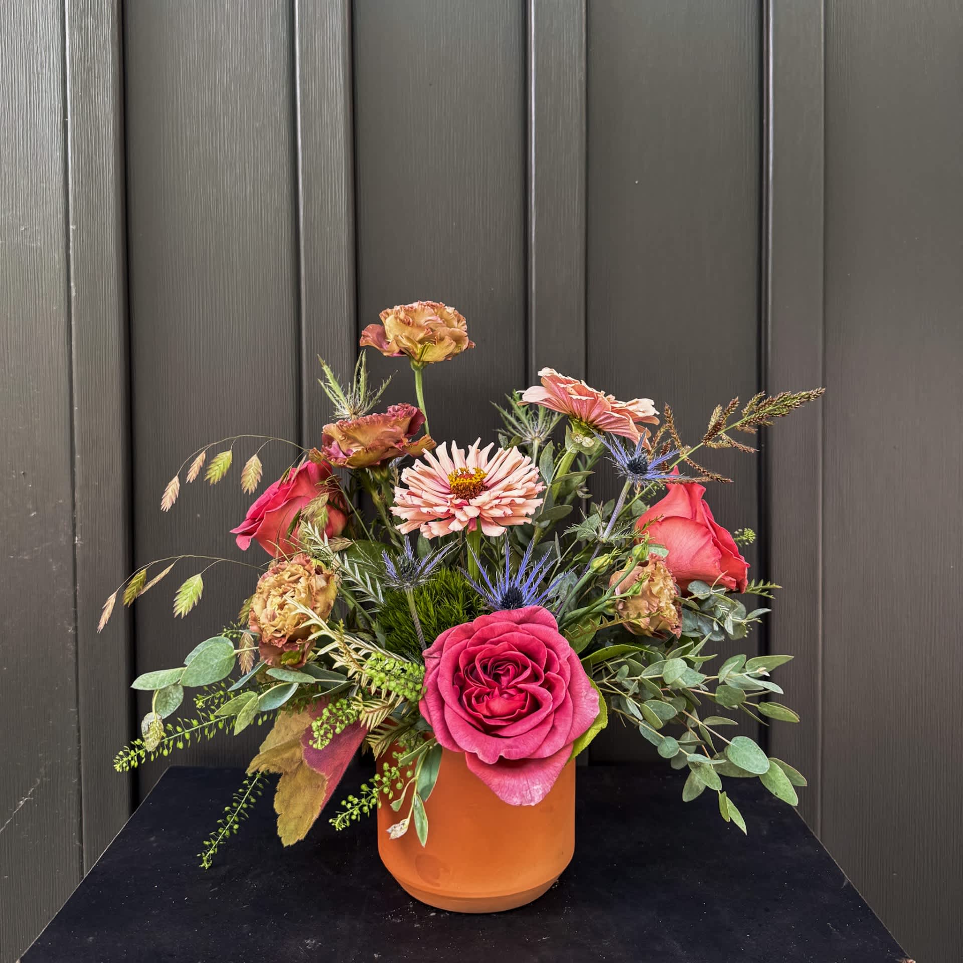 Mixed bouquet of pink and peach flowers in an orange vase