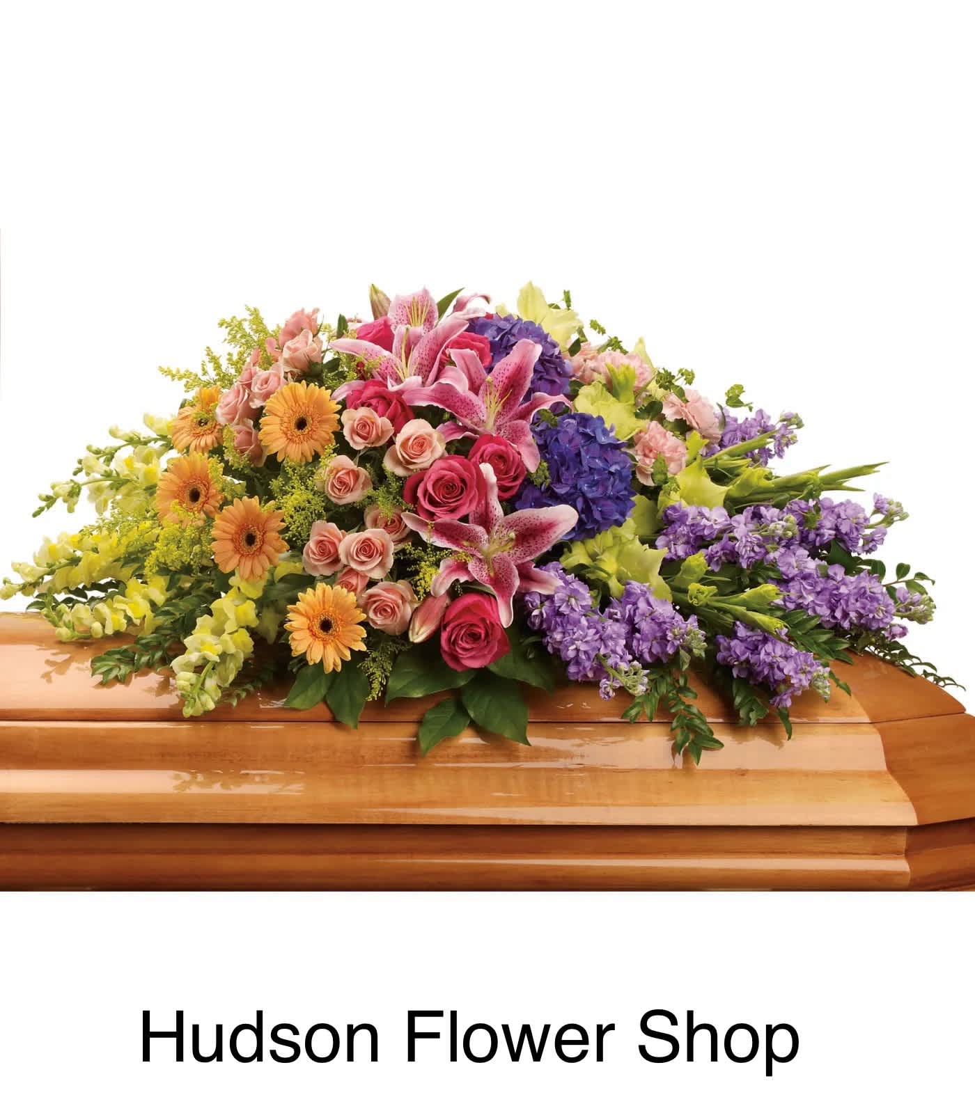 Colorful floral casket spray with pink lilies, roses, gerberas, and purple blooms