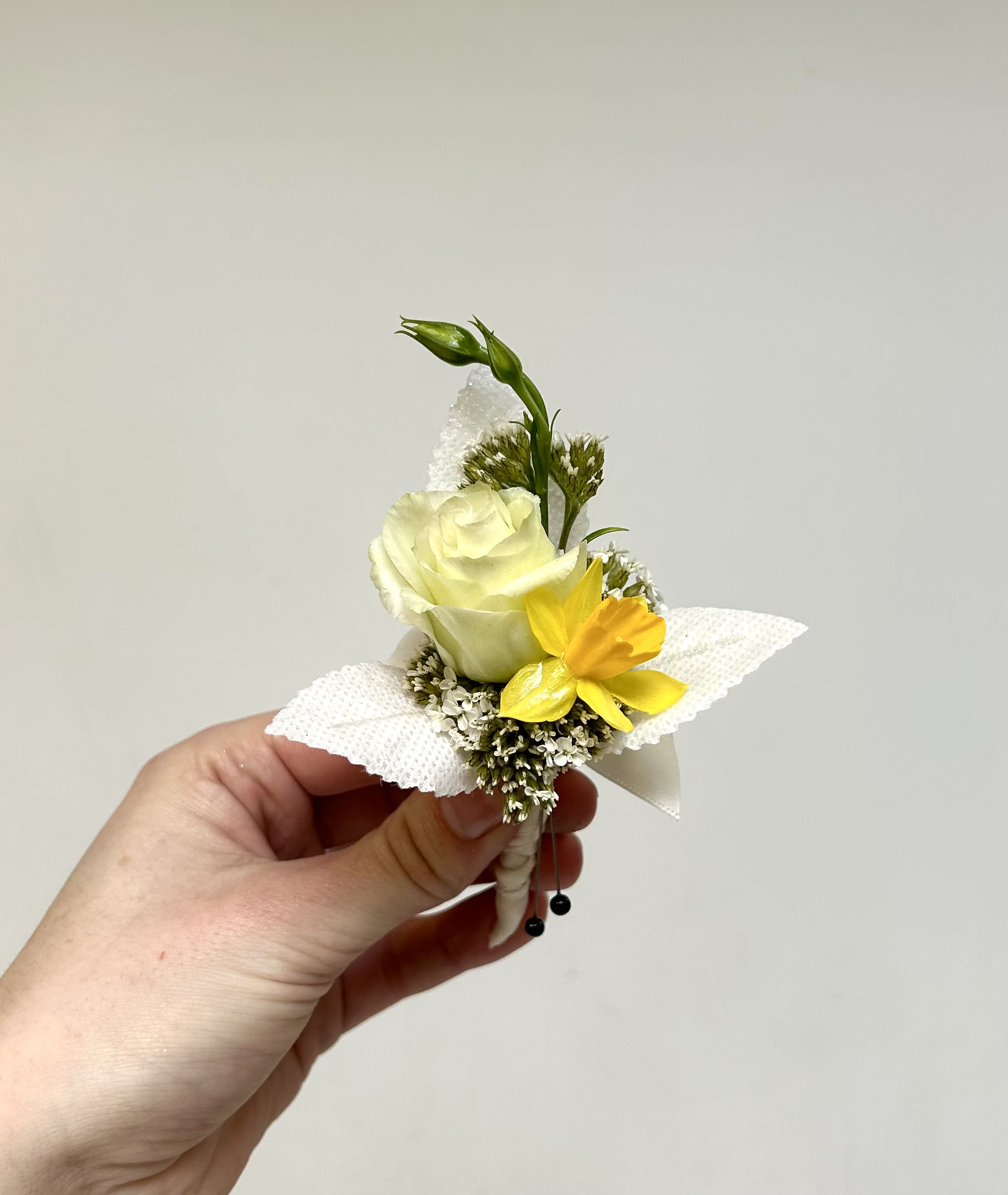 Yellow &amp; White Mixed Boutonniere - Perfect for a prom or wedding, this compact boutonniere is designed to make the person wearing it feel polished and noticed without overpowering their outfit.  Carefully wired and finished with a white textured fabric wrap, the stem is secured with black bead pins for a crisp, formal touch. The soft palette of white, yellow, and green reads light and elegant, and the hand-tied size makes it easy to pin to a lapel or dress. If you have flower preferences, note them in special instructions and we'll try to accommodate requests.