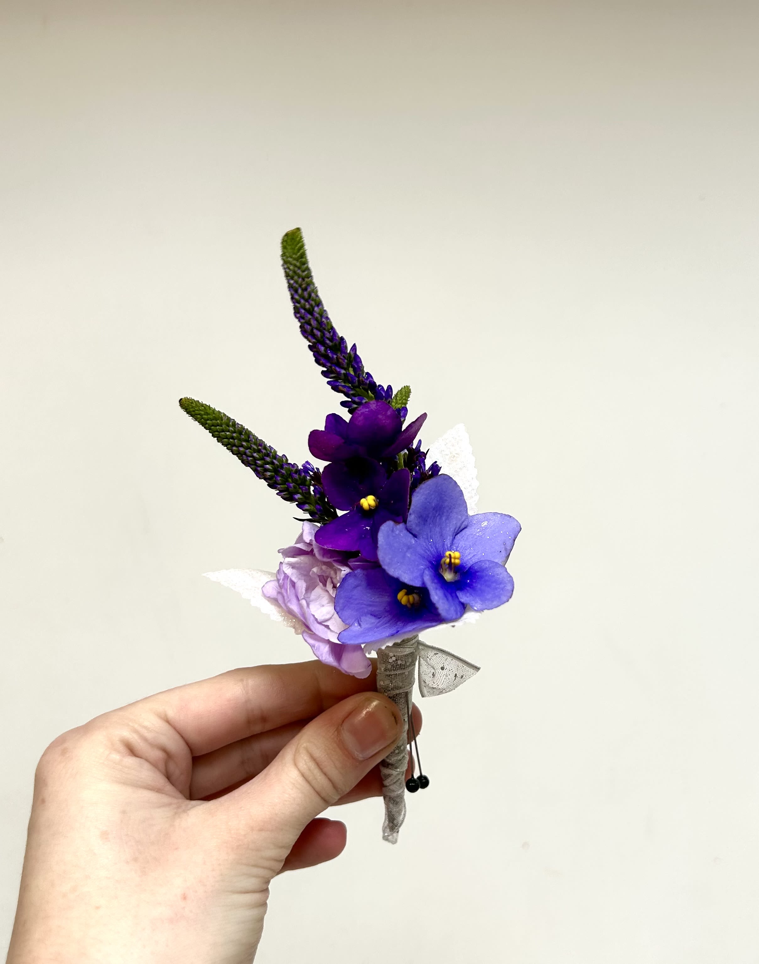 Purple Boutonniere - Clustered purple and blue blooms form a compact, upright boutonniere that makes a confident, modern statement for prom or any formal occasion.   Lavender accents and small touches of white and pink soften the color story, while the stems are neatly wrapped in pale fabric and finished with a slender ribbon for a refined, wearable look. Sized for a lapel, this petite boutonniere is designed as a formal accessory-durable enough for an evening of photos and dancing yet delicate in appearance.  Perfect for prom, weddings, or special nights when you want someone to feel both elegant and a little whimsical. If you prefer specific flowers or color emphasis, add a note in the special instructions and we'll do our best to accommodate. Handle with care and keep cool until placement to preserve freshness.