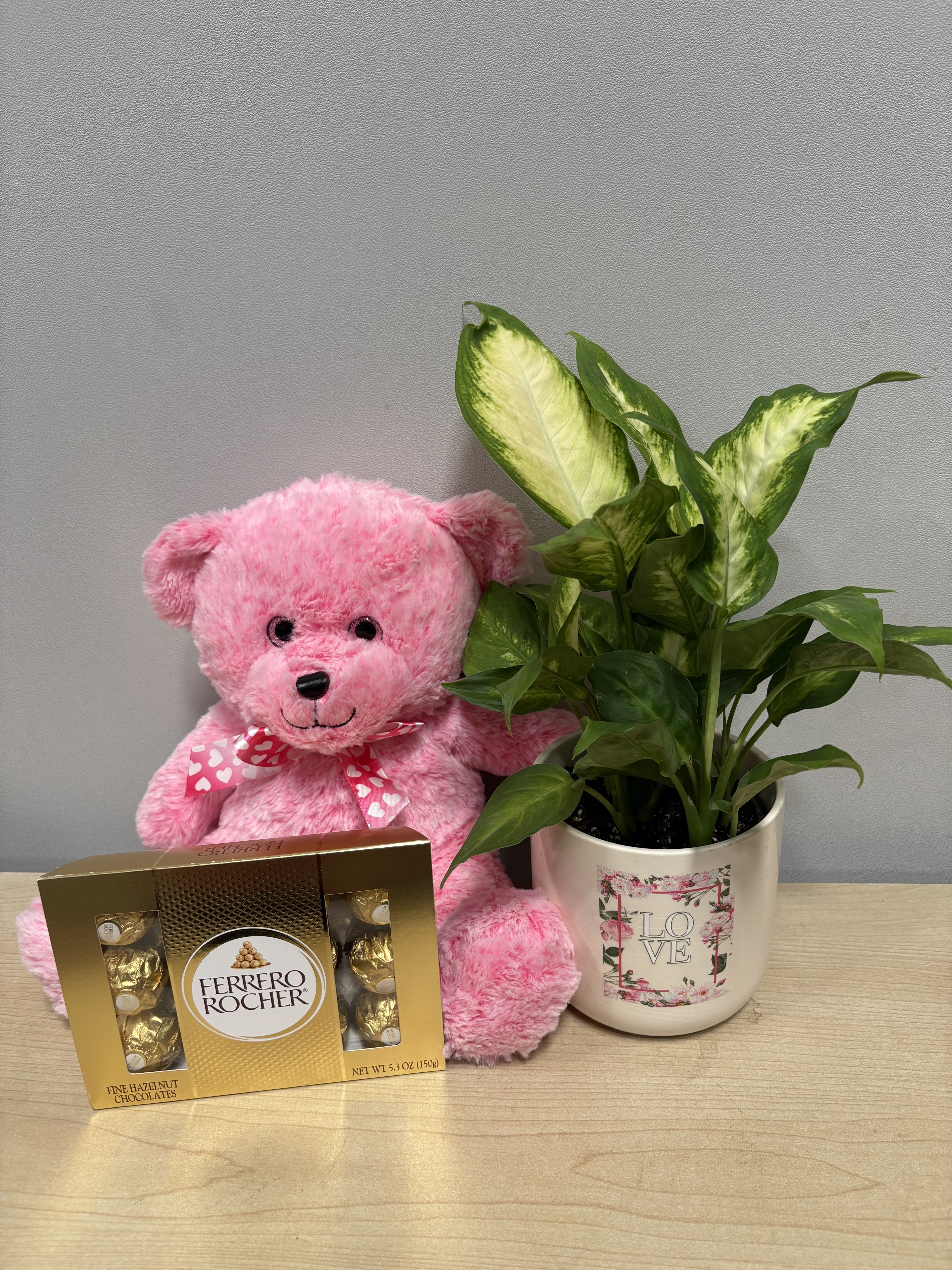 Pink teddy bear with chocolates and a potted plant in a love-themed mug
