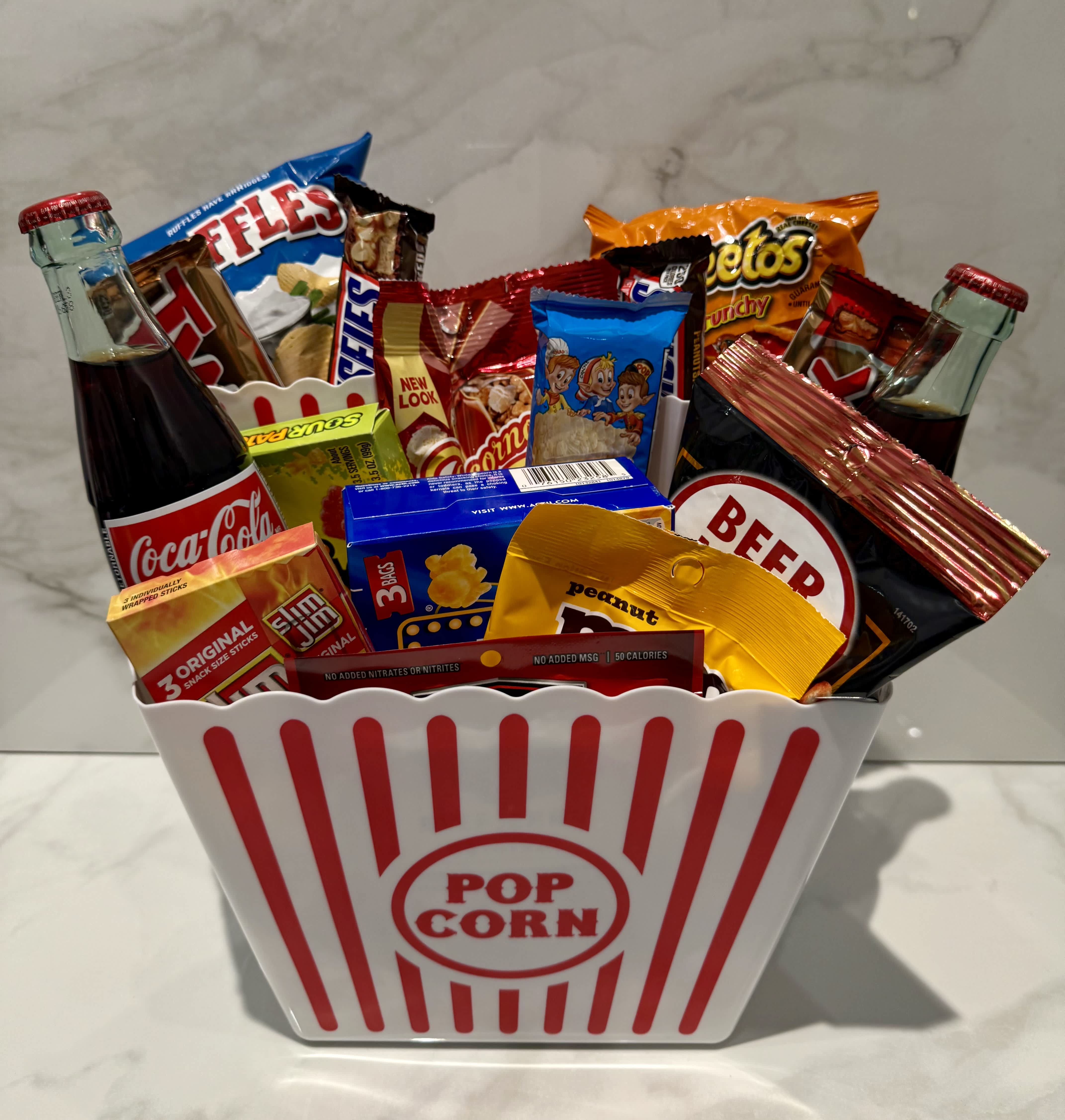 Popcorn bucket filled with soda bottles and assorted snack packs