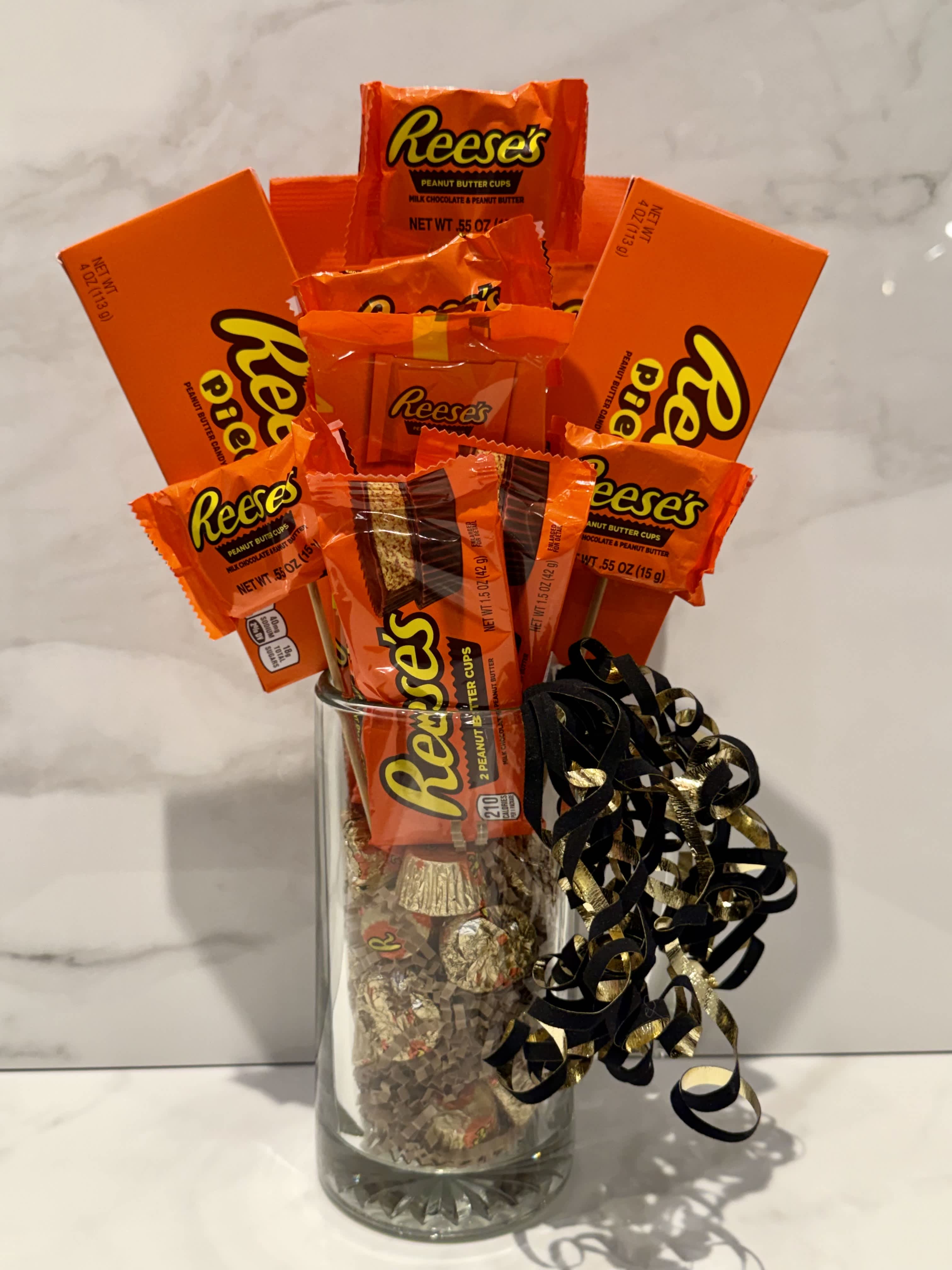 Reese's candy bouquet in a clear glass vase with black and gold ribbon curls