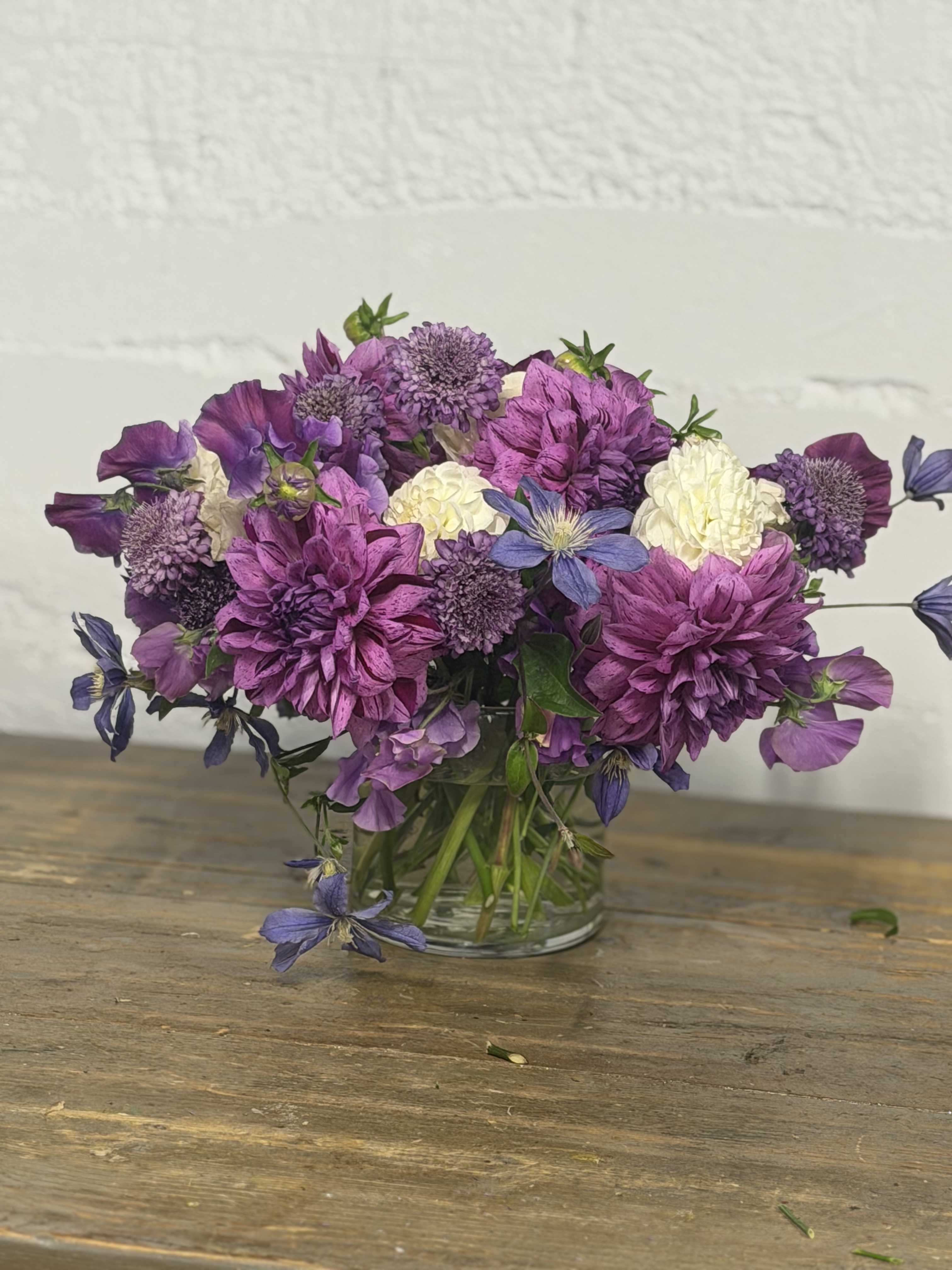 Purple and white mixed bouquet in a clear glass vase