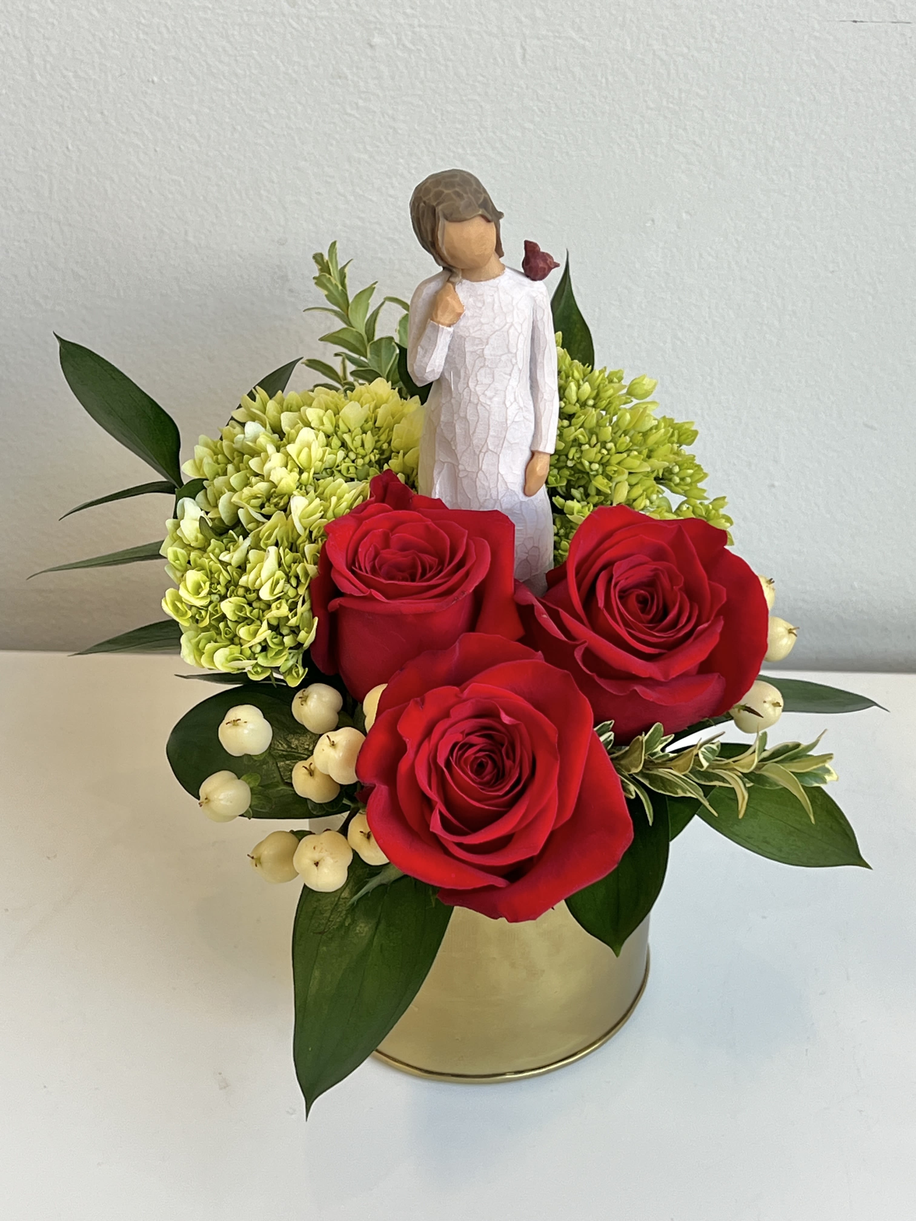 Red roses with green hydrangeas and a figurine in a gold container