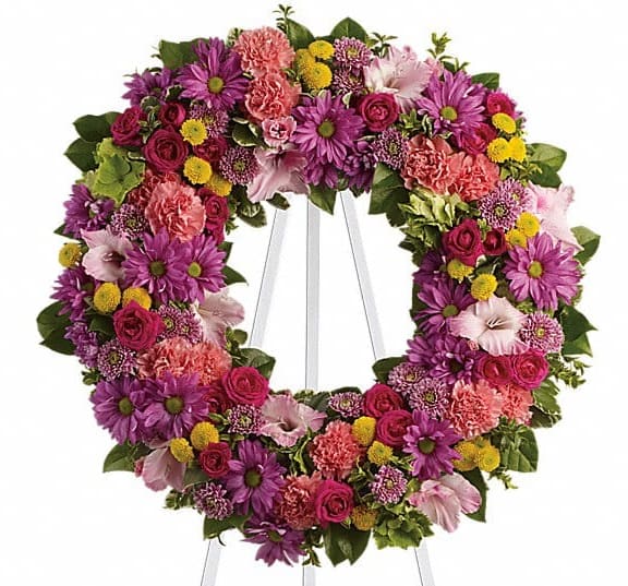 Colorful floral wreath on a white stand with purple, pink, and yellow blooms